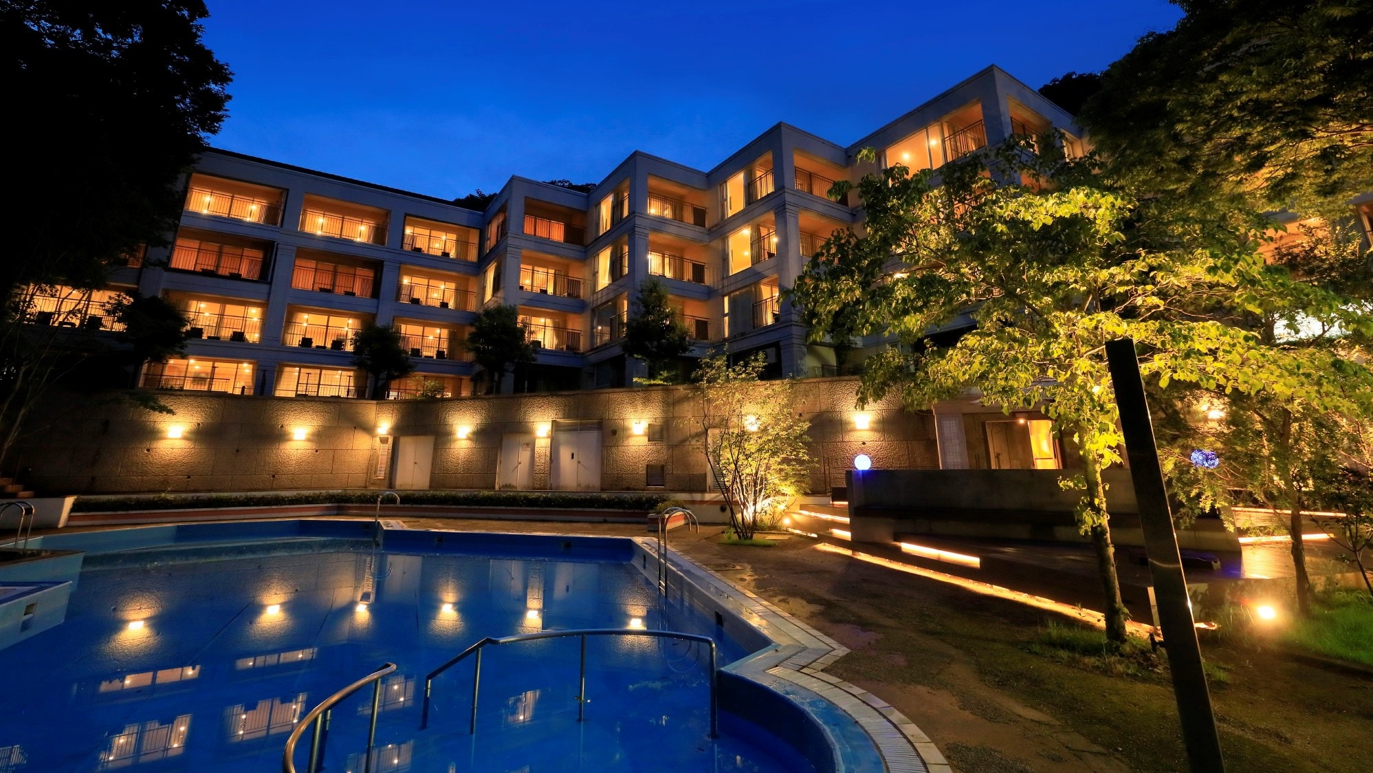 The illuminated hotel is beautifully reflected on the water's surface, creating a fantastical night view. (Example)