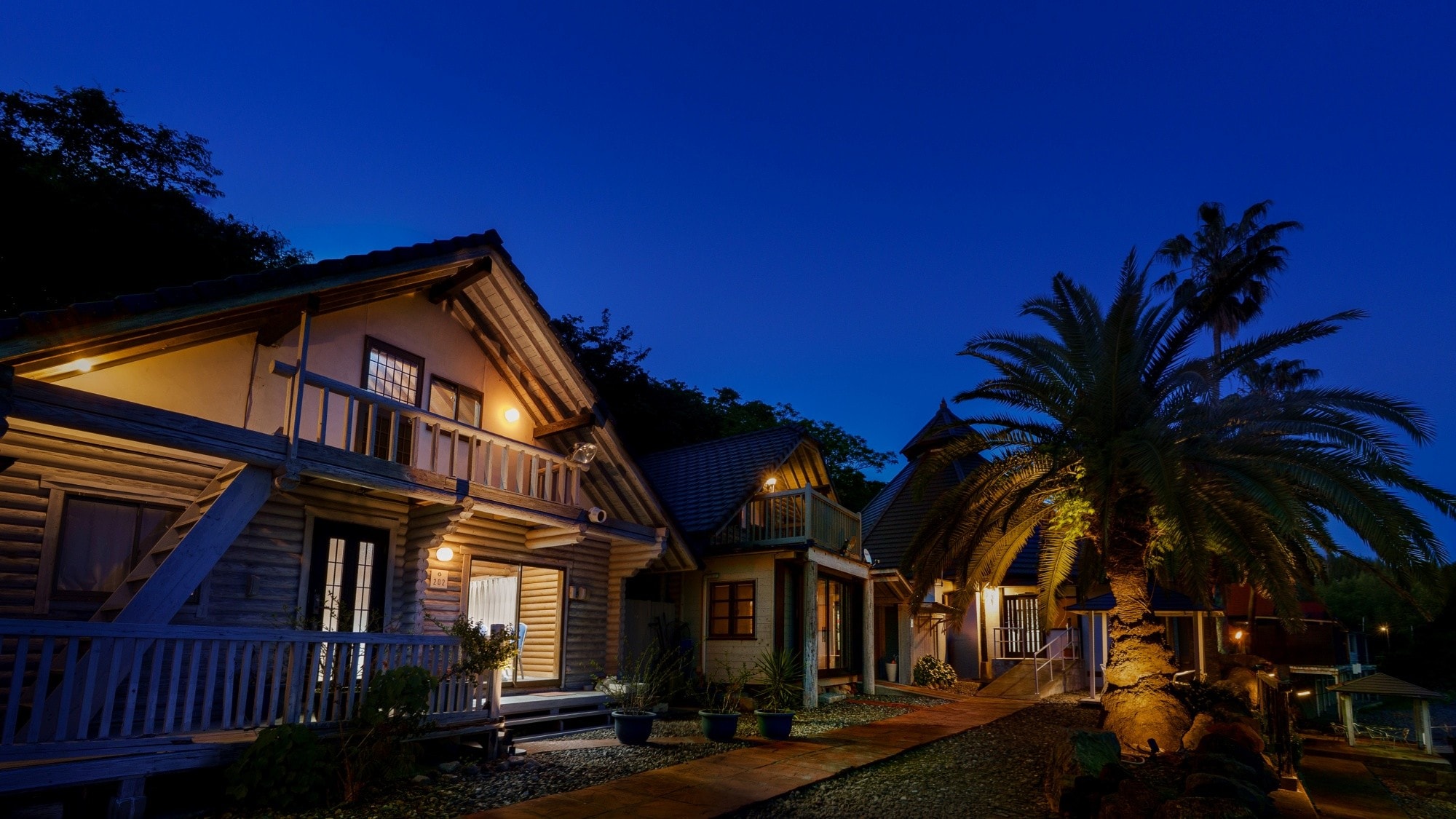 [Cottage Exterior] A hidden resort at night, illuminated by soft lights, creating a special night filled with exotic charm.