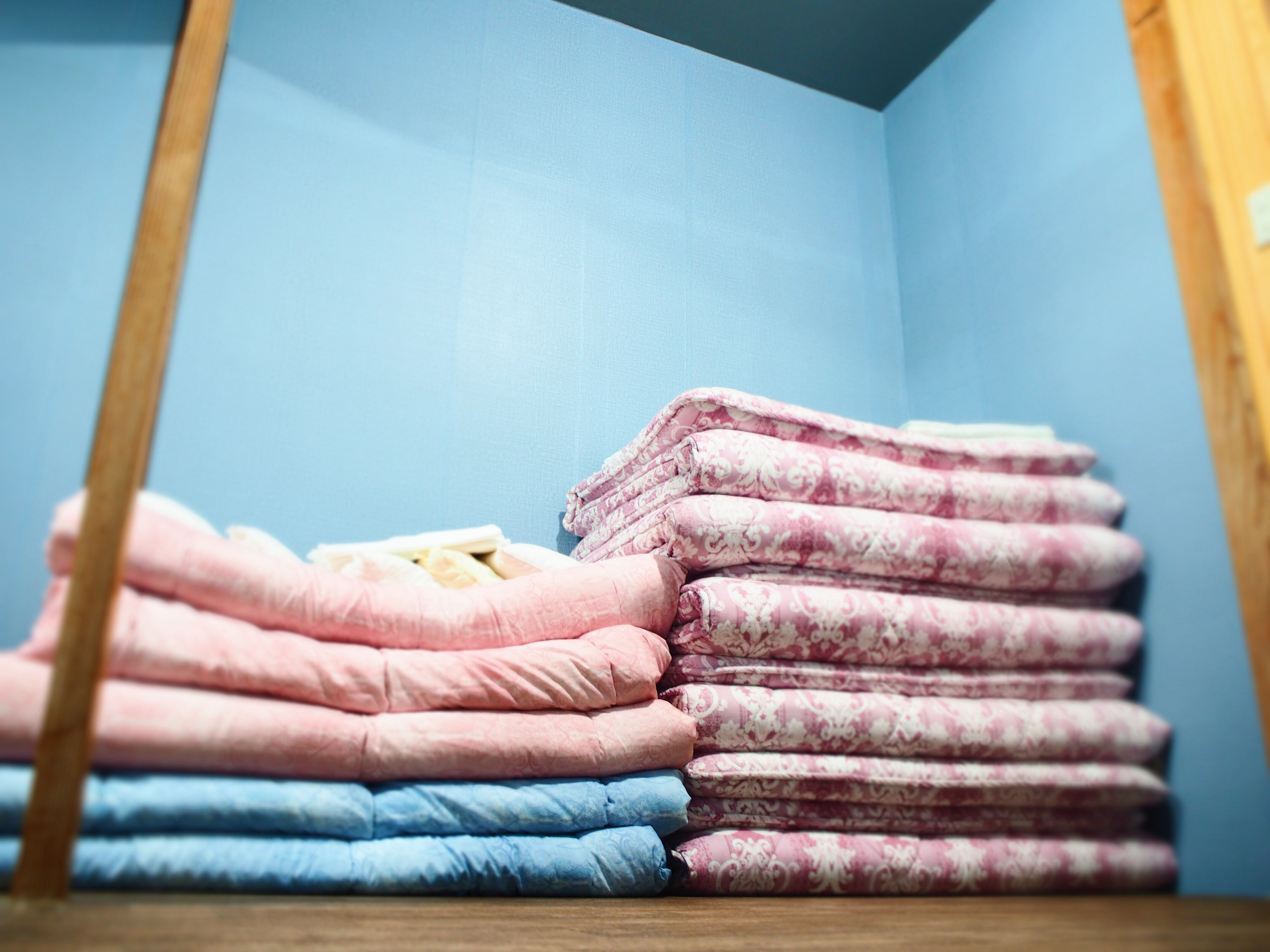A futon for sleeping on a pile of clothes. The floor is covered with a soft mat.