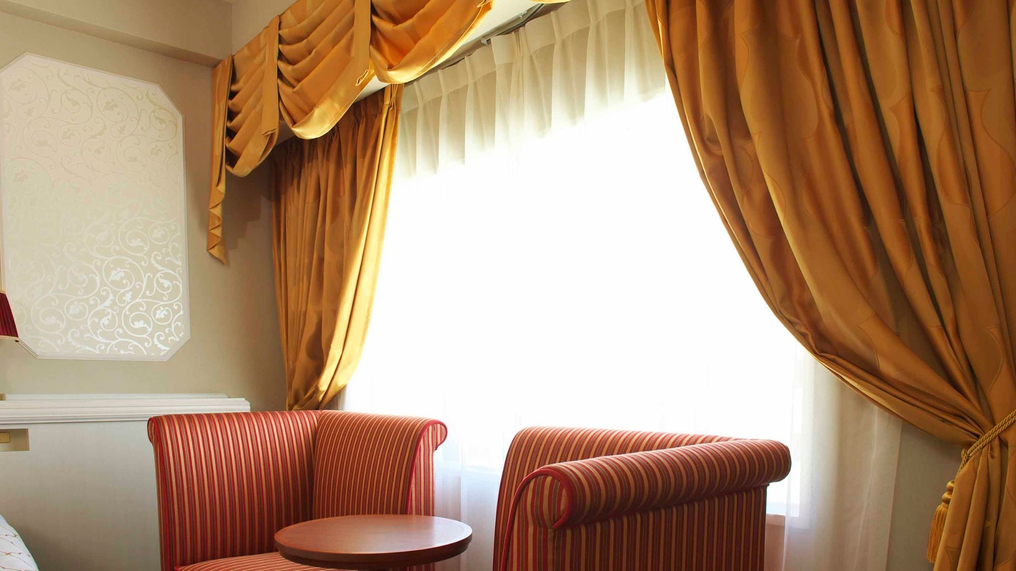 Sofa klasik dan tirai menjuntai menambah sentuhan elegan.