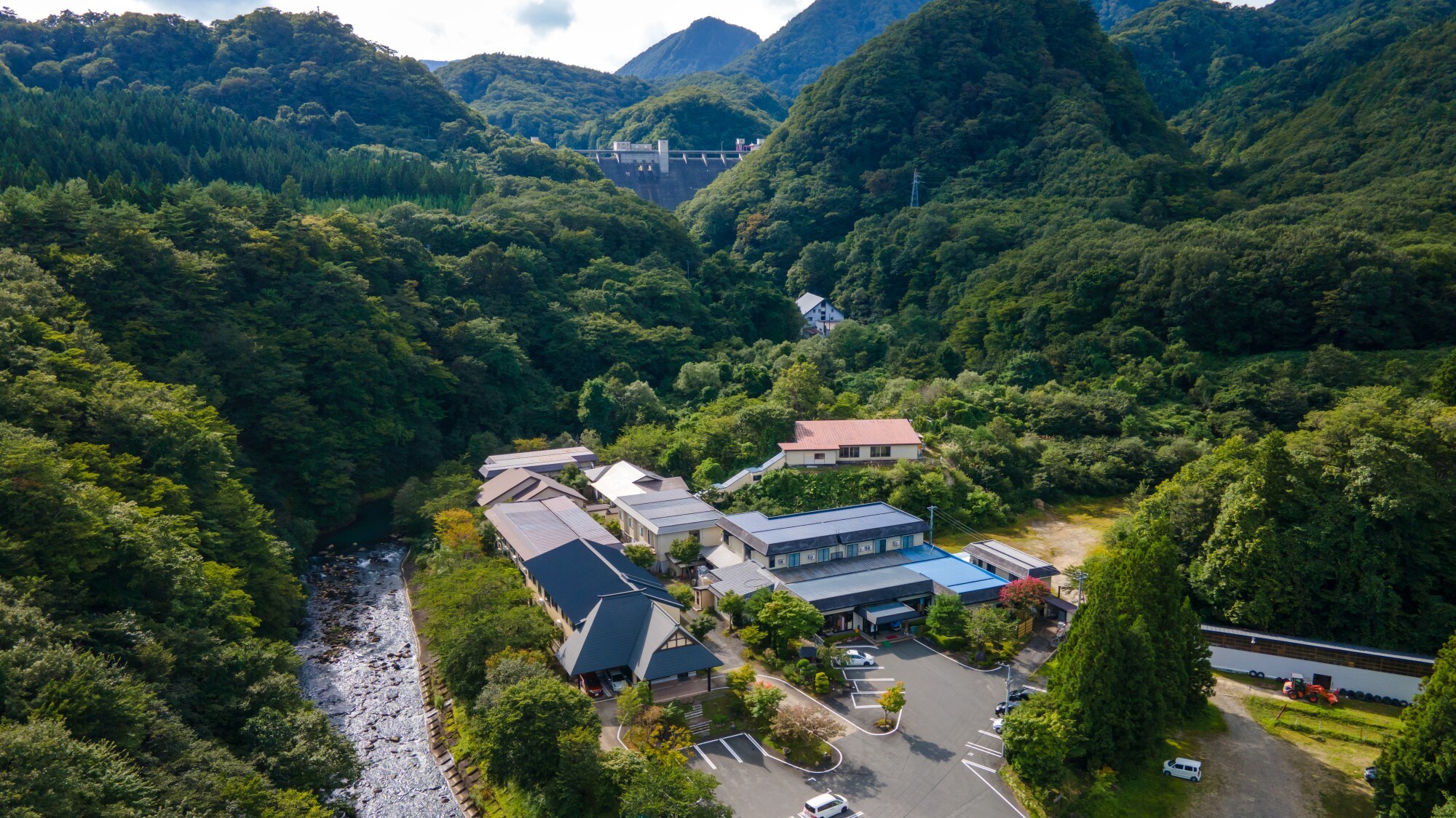 [Exterior] A vast mountain inn. New building: paulownia flower (left) along the river, main building: Yamabuki flower (right) on the mountain side