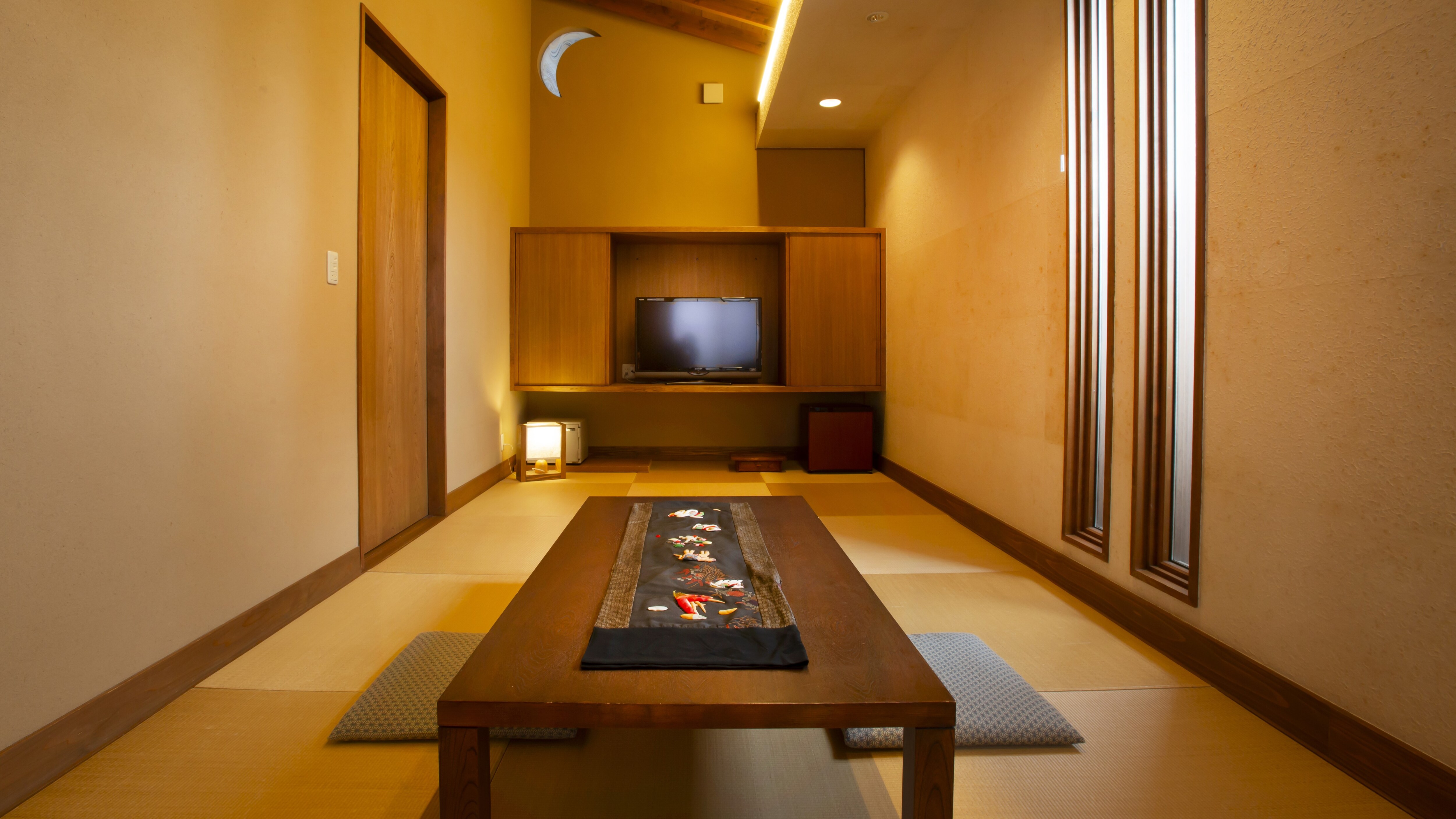[New Wing - Akizuki] This Japanese-style room is themed around autumn, with the soft light filtering in through the small moon-shaped window and shoji screens, blocking out the outside world.