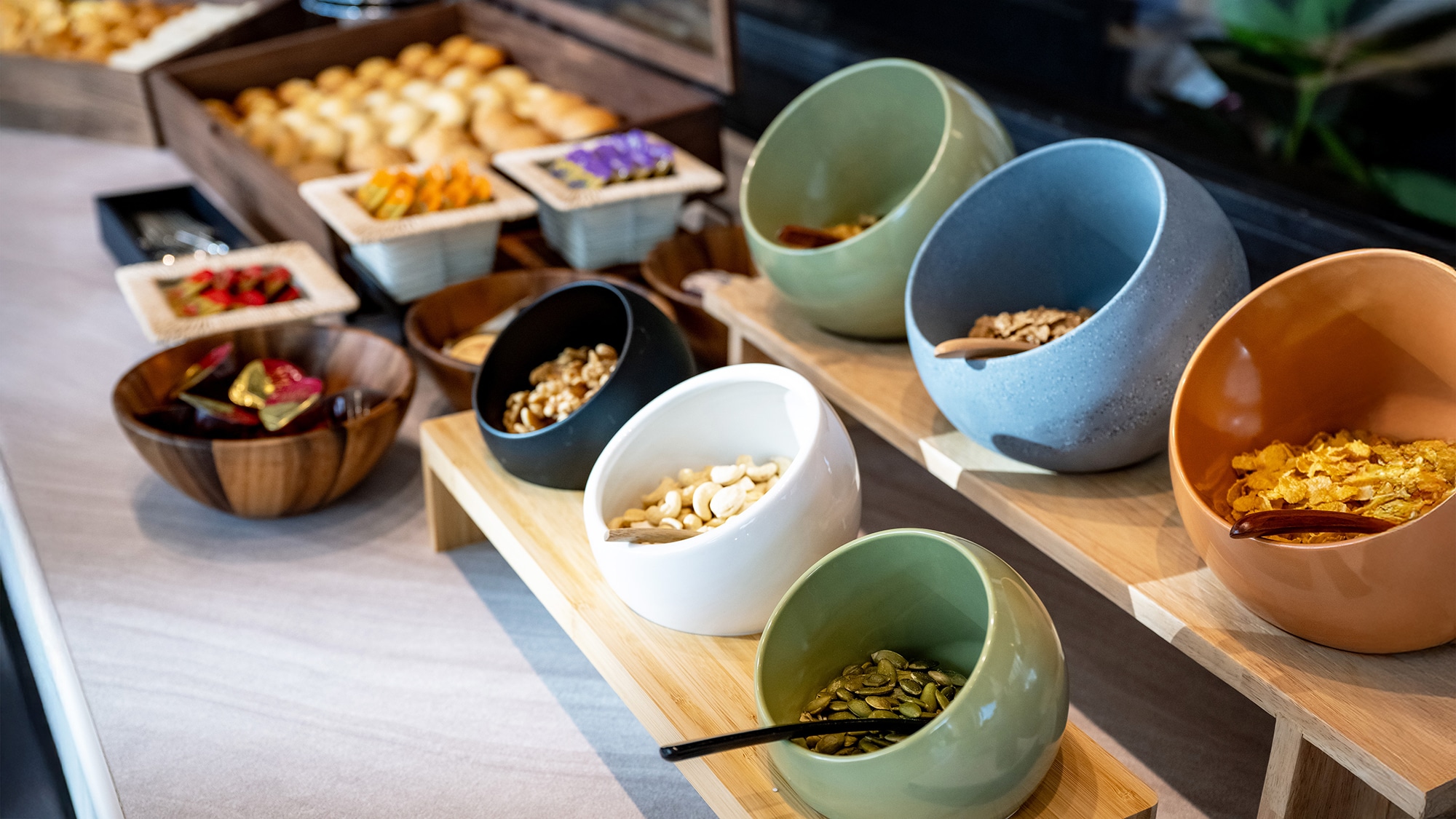 A breakfast buffet corner with a wide variety of toppings, including nuts and cereals
