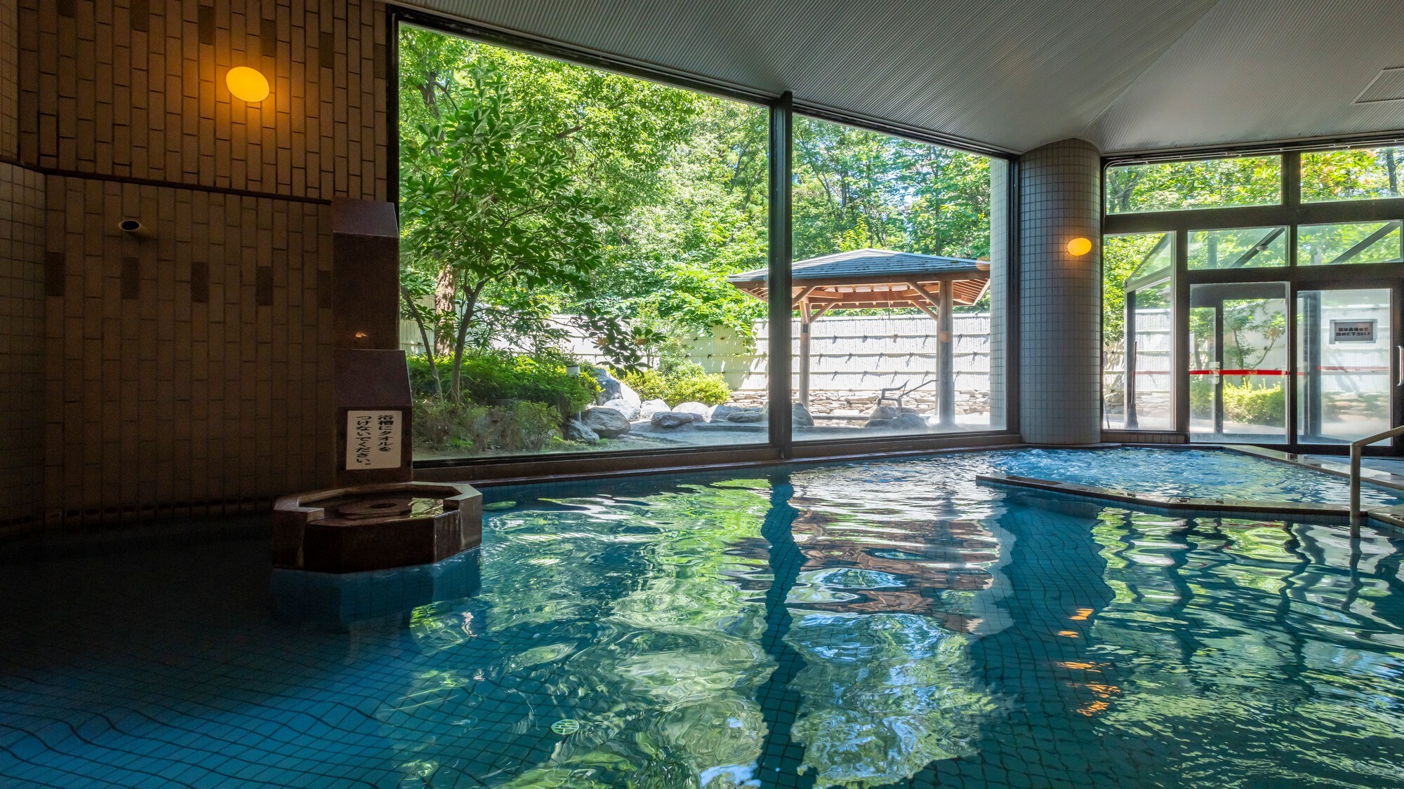 Large communal bath and open-air bath surrounded by greenery