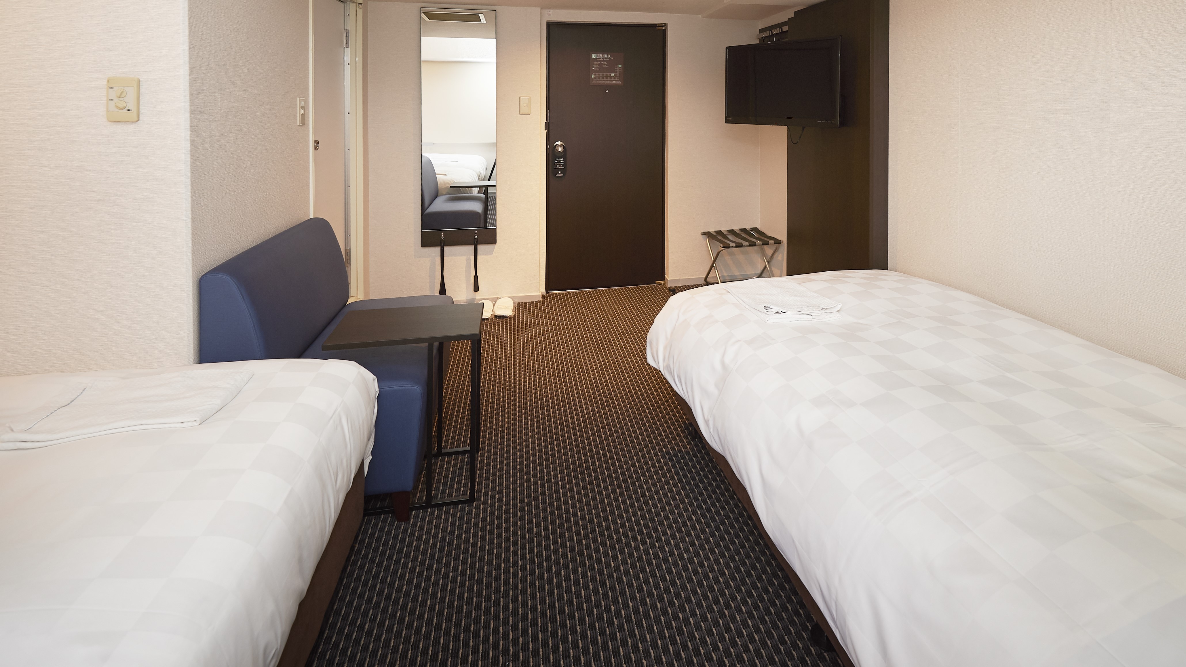 Triple/A room with three single beds and a mini sofa. (Example of a guest room)