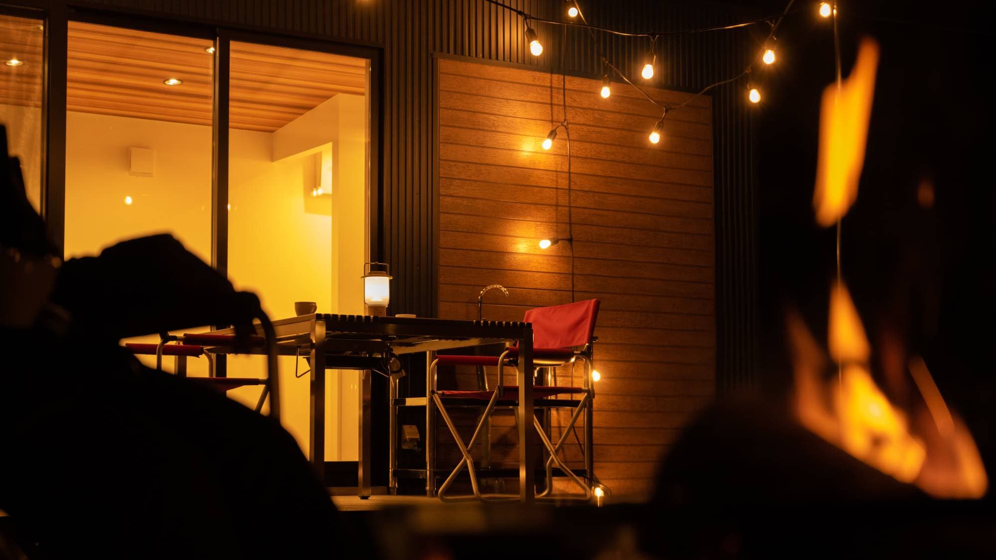 Under the quiet, starry night sky, the flickering light of the bonfire creates a relaxing moment.