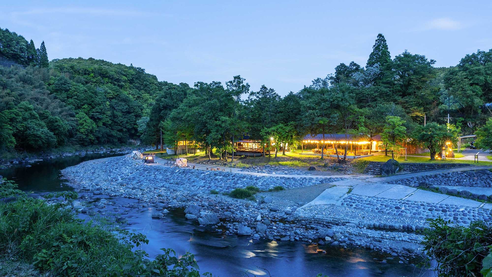 ・[Exterior/Night] Enjoy a special time in the forest by the clear stream, with a BBQ and sauna lit up by night lights.