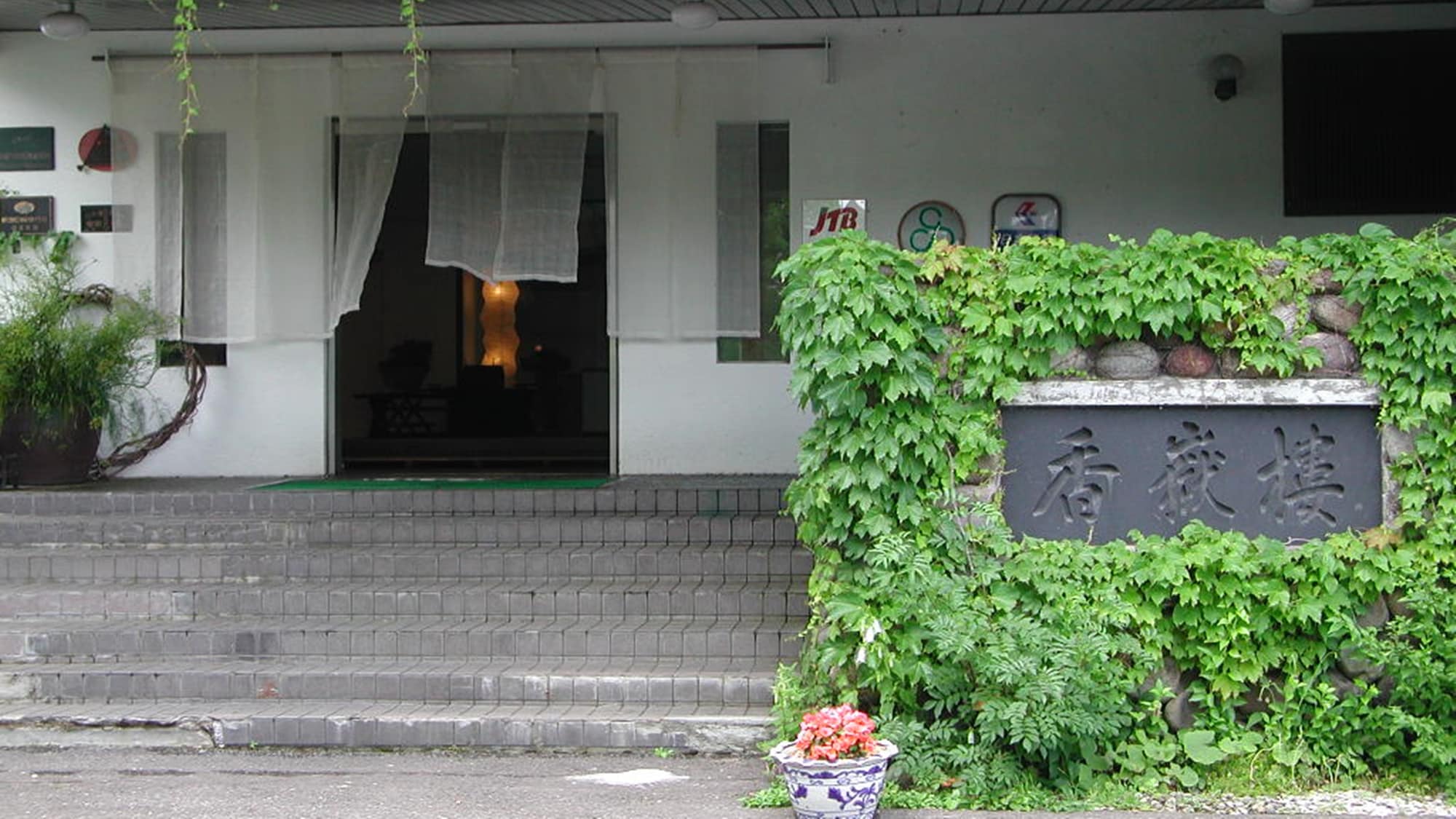 *The hotel's entrance (green season) A classical Western-style entrance with greenery that stands out against the white exterior walls.