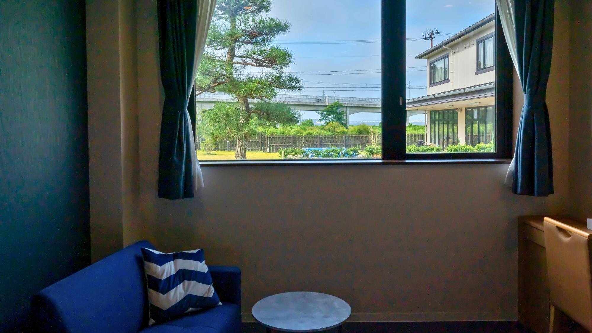 Comfort Twin "Umi Modern" is a room with a sofa set by the window and a relaxing view of the courtyard.