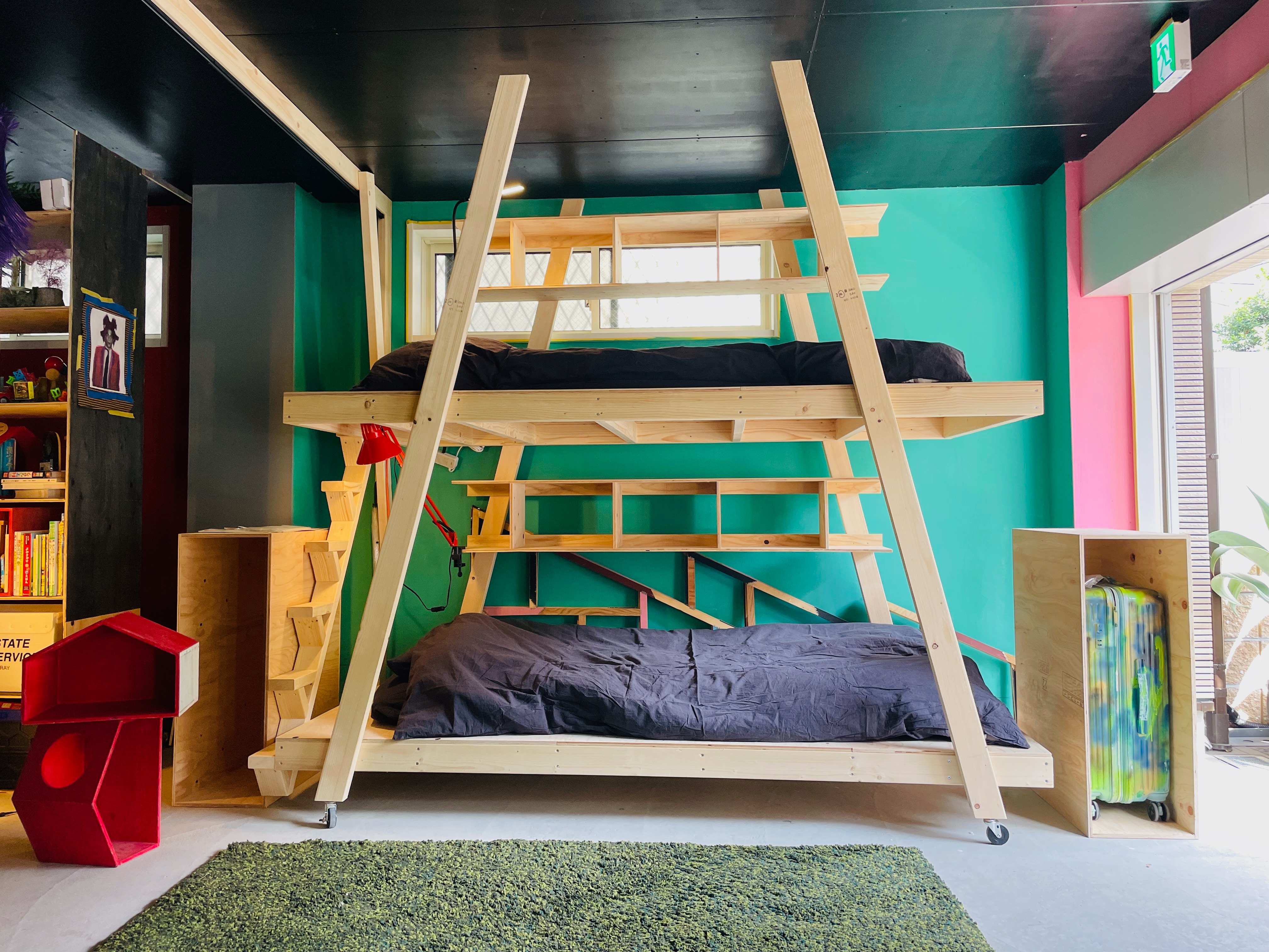 Next to the bed, there is a wooden box for neatly storing suitcases.