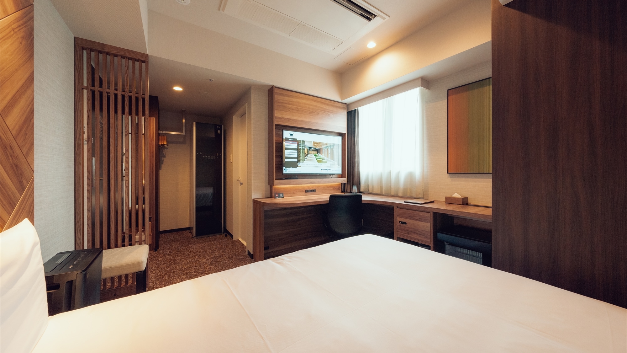 The double room has a spacious L-shaped desk and a chair with a backrest, making it ideal for desk work.