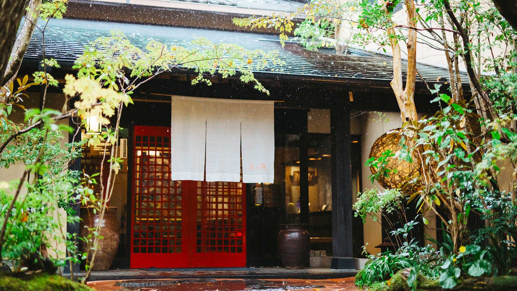 [Exterior/Entrance] The entrance is surrounded by greenery. The gentle light of the ball lanterns is soothing.