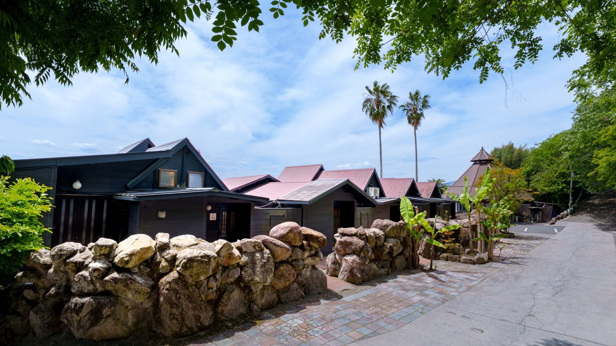 [Lodge Exterior] The six lodges are surrounded by banana trees, creating a tropical resort atmosphere.