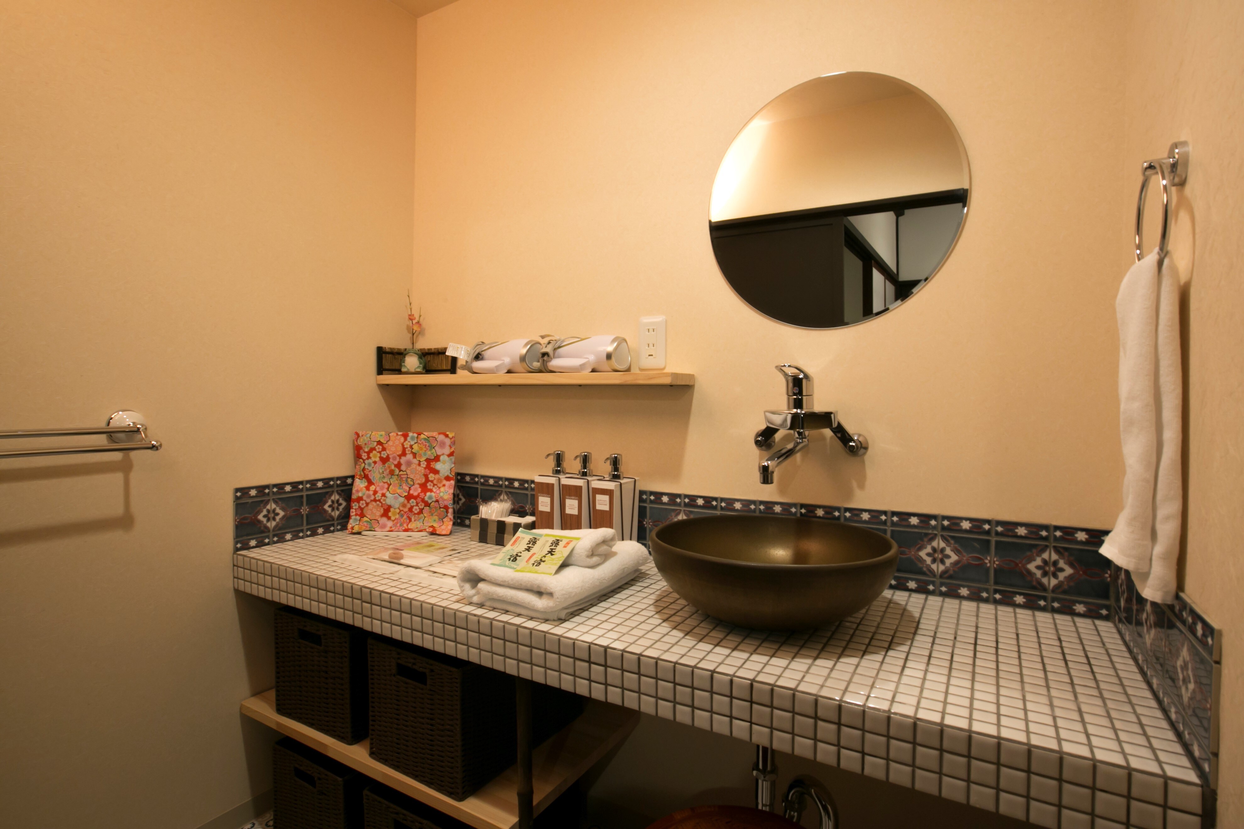 The bathroom is decorated with cute retro tiles. The washbasin is made of Shigaraki ware, matching the bathtub.