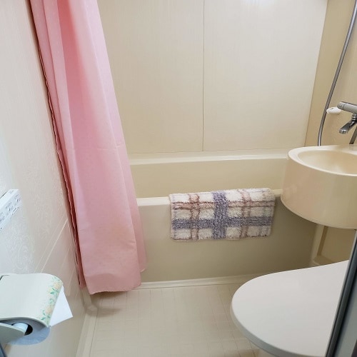 ・ The unit bath has a shower curtain and a foot-wiping mat.