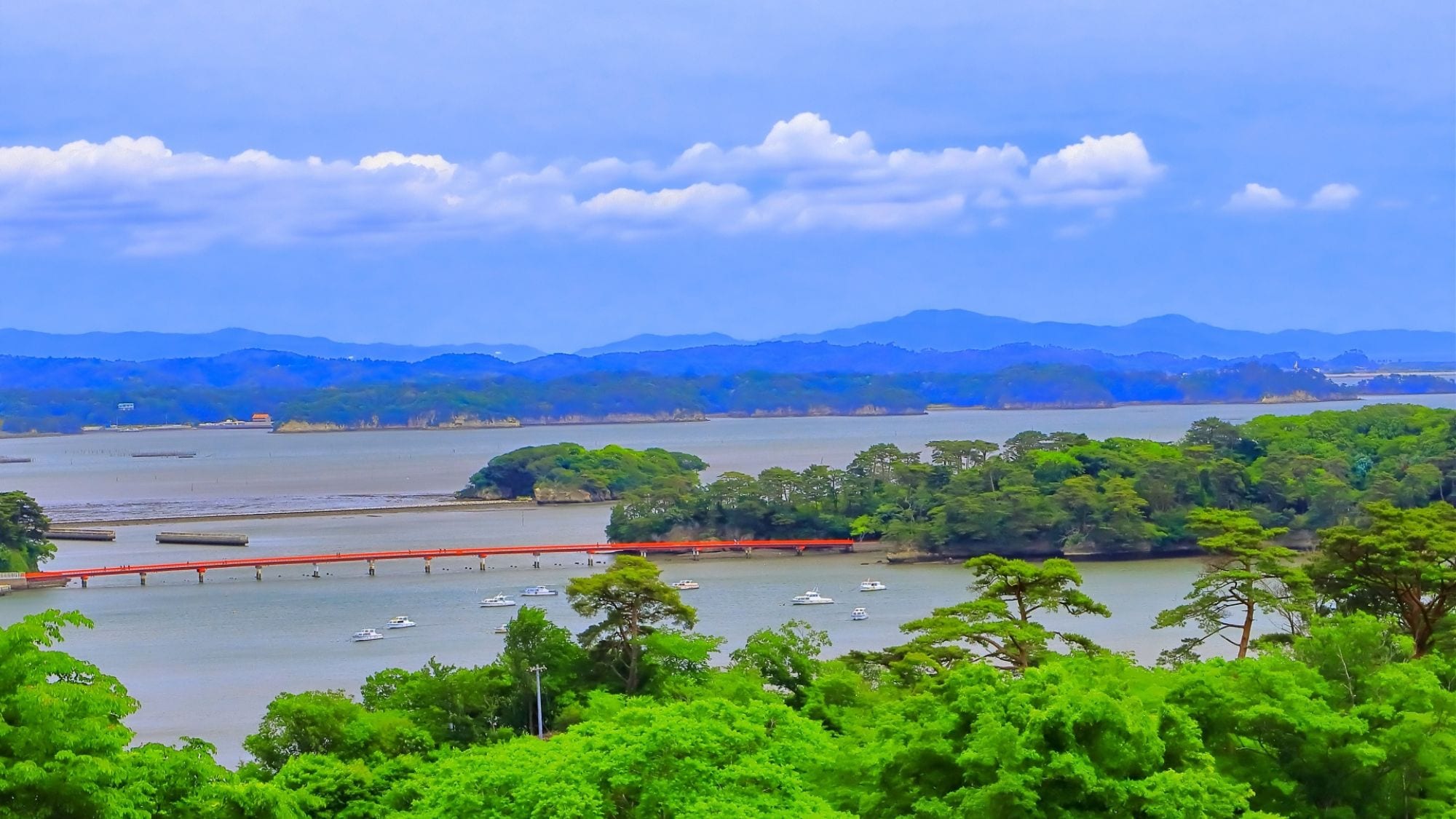 [Dari Taman Saigyo-Modoshi-no-Pine] Kehijauan yang cemerlang, langit dan laut biru, serta jembatan berwarna merah terang merupakan pemandangan unik di Matsushima.