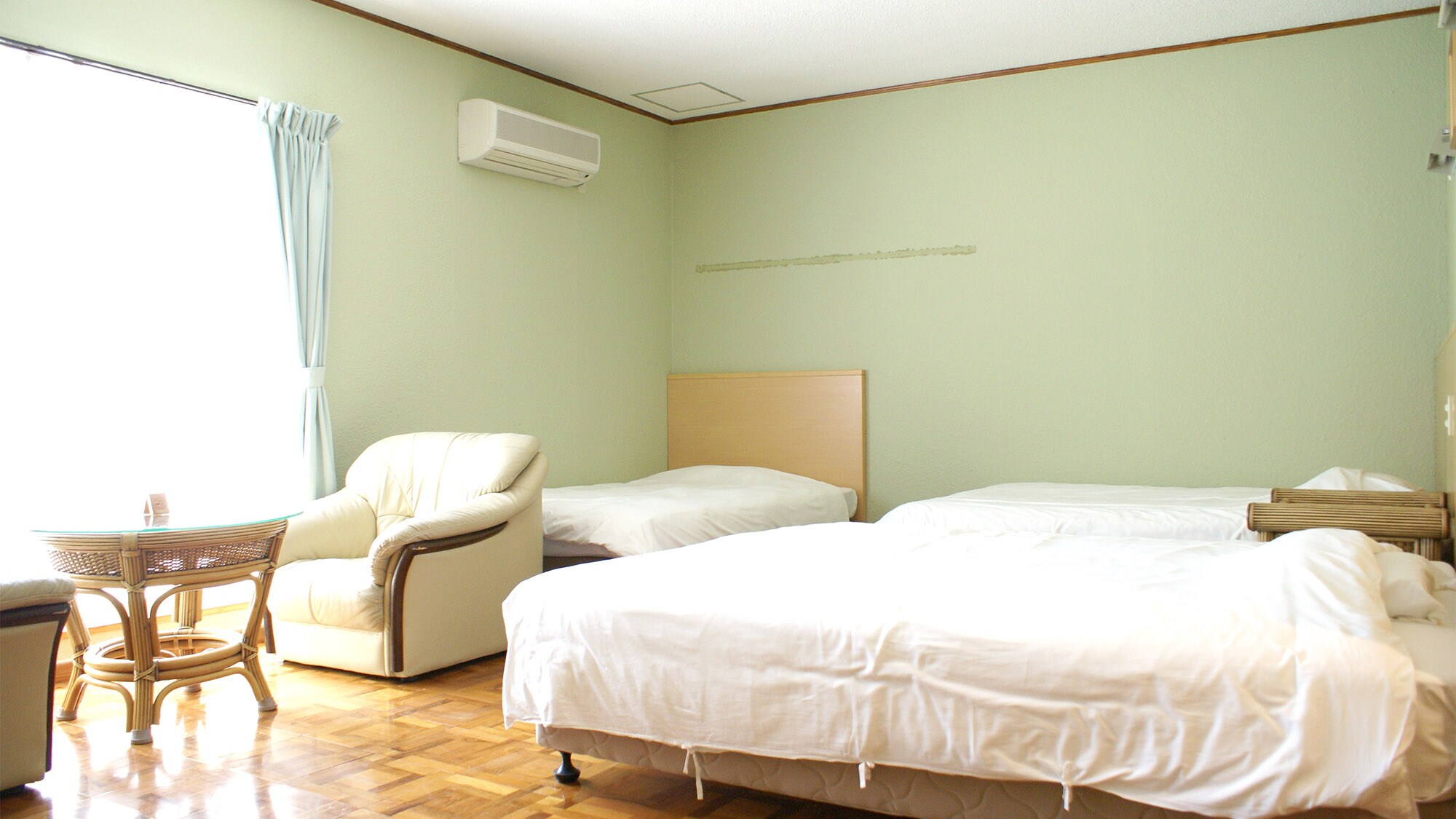 Kamar Triple: 3 tempat tidur dan meja & kursi dipasang di ruang yang luas.