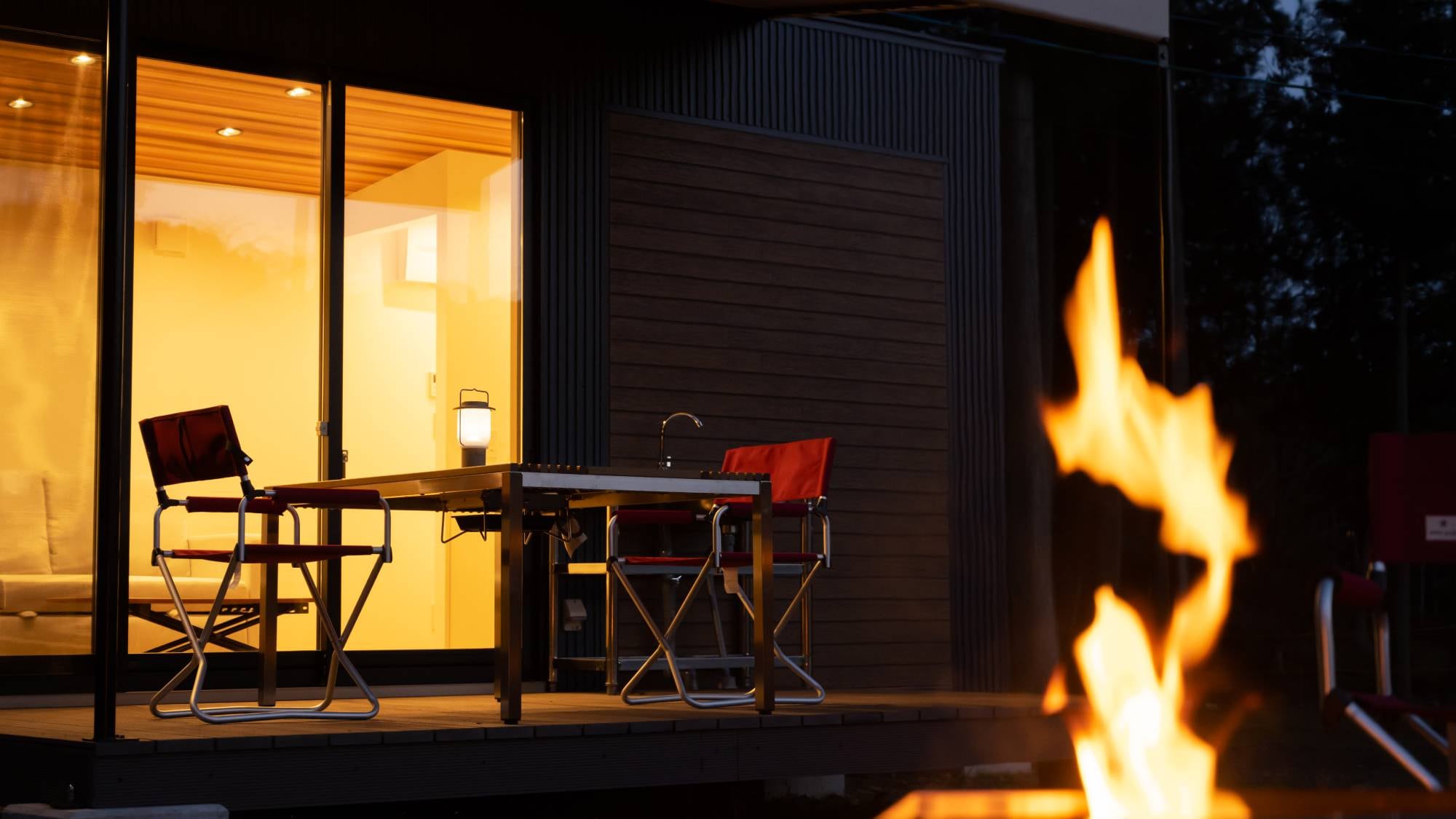 Under the quiet, starry night sky, the flickering light of the bonfire creates a relaxing moment.