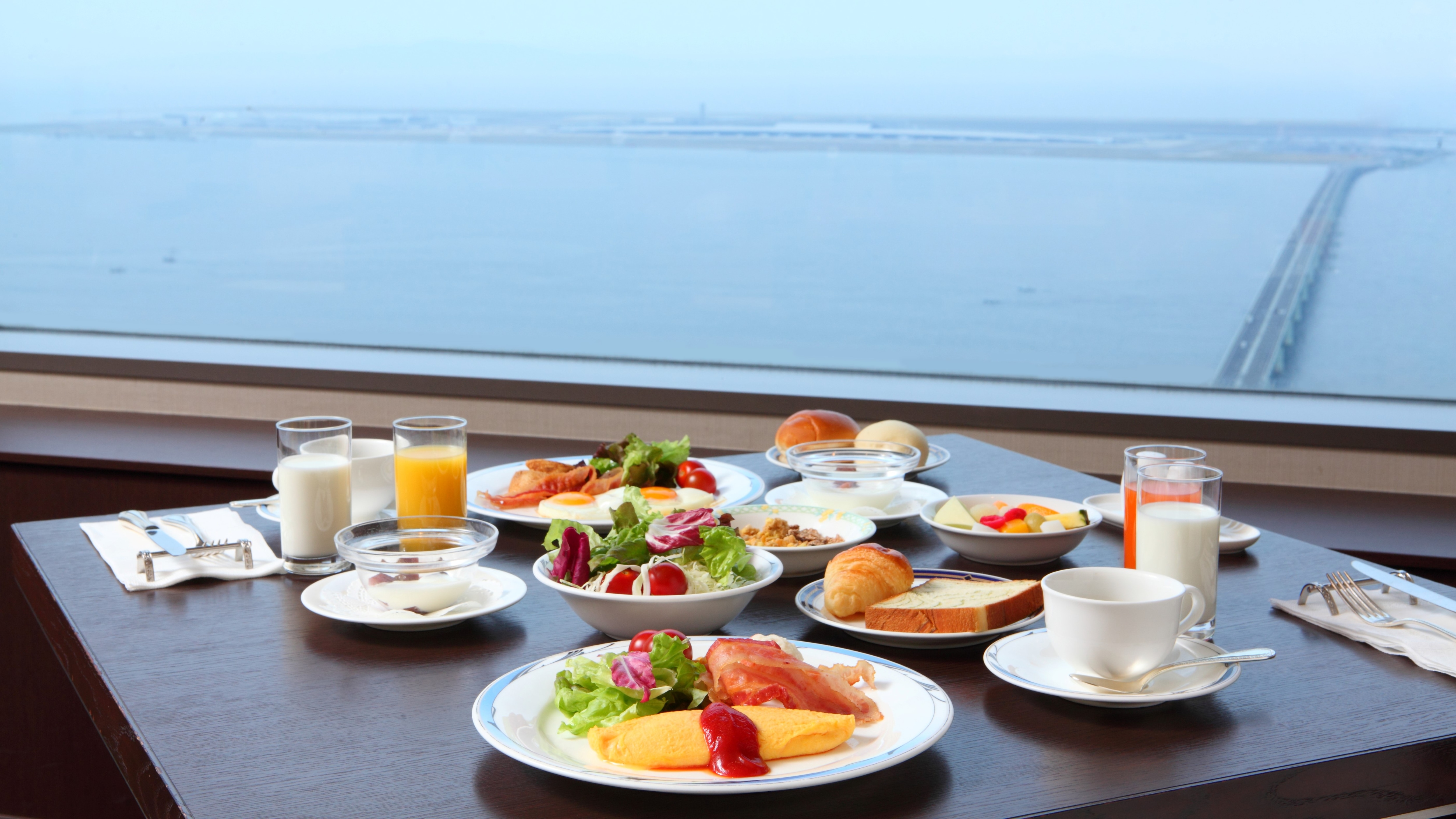 早餐自助餐在飯店頂樓的餐廳。一邊眺望大海、天空和城市景觀，一邊享受奢華時光。