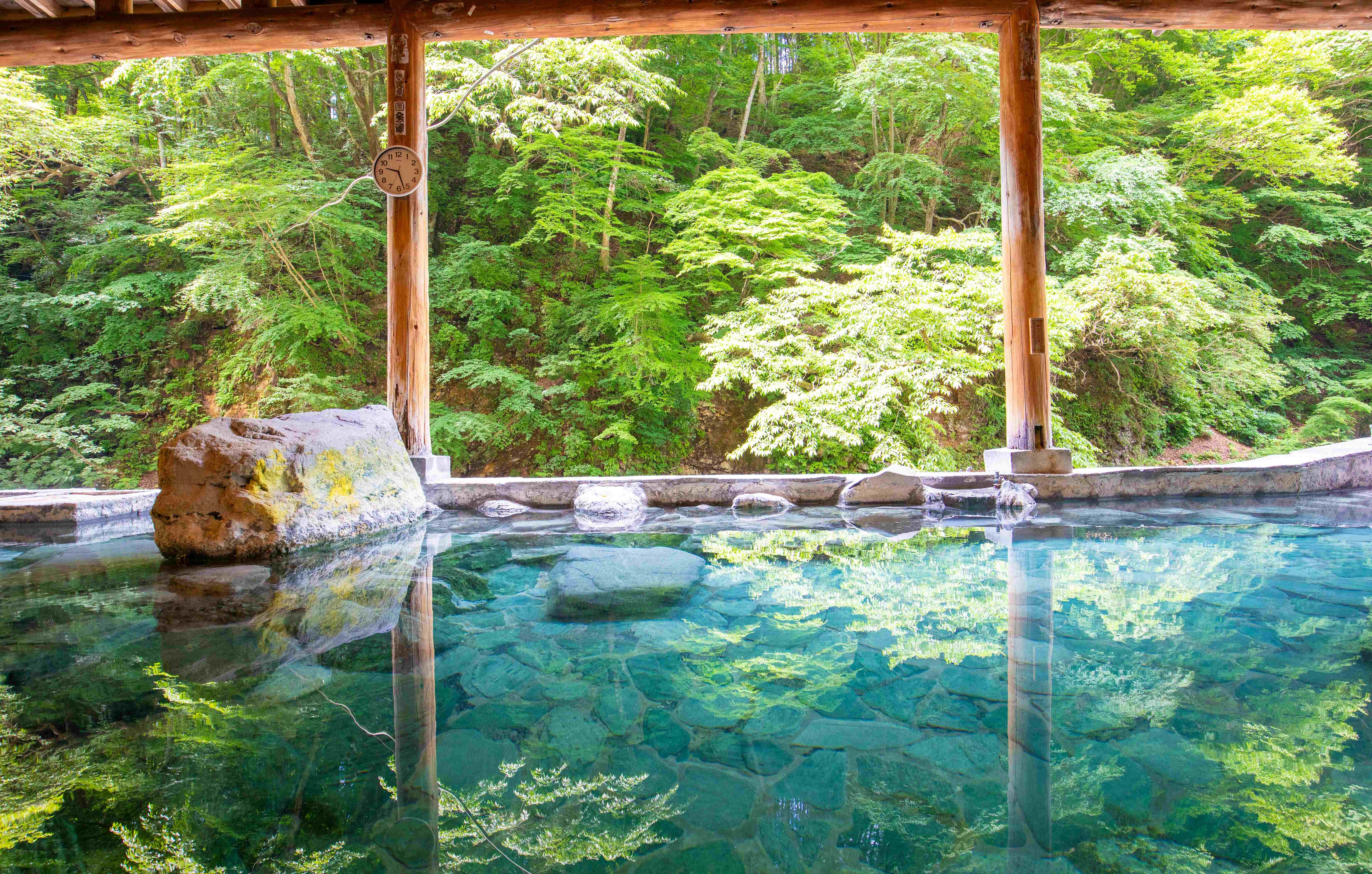 [Open-air bath with a sacred theme] A rock bath overlooking the Shimagawa River; the water is hotter near the large rock inscribed with a sermon.