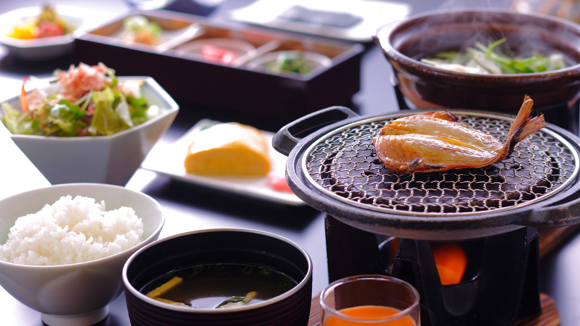 A Japanese breakfast with a wide variety of items such as freshly made omelet rolls and three small bowls (image)