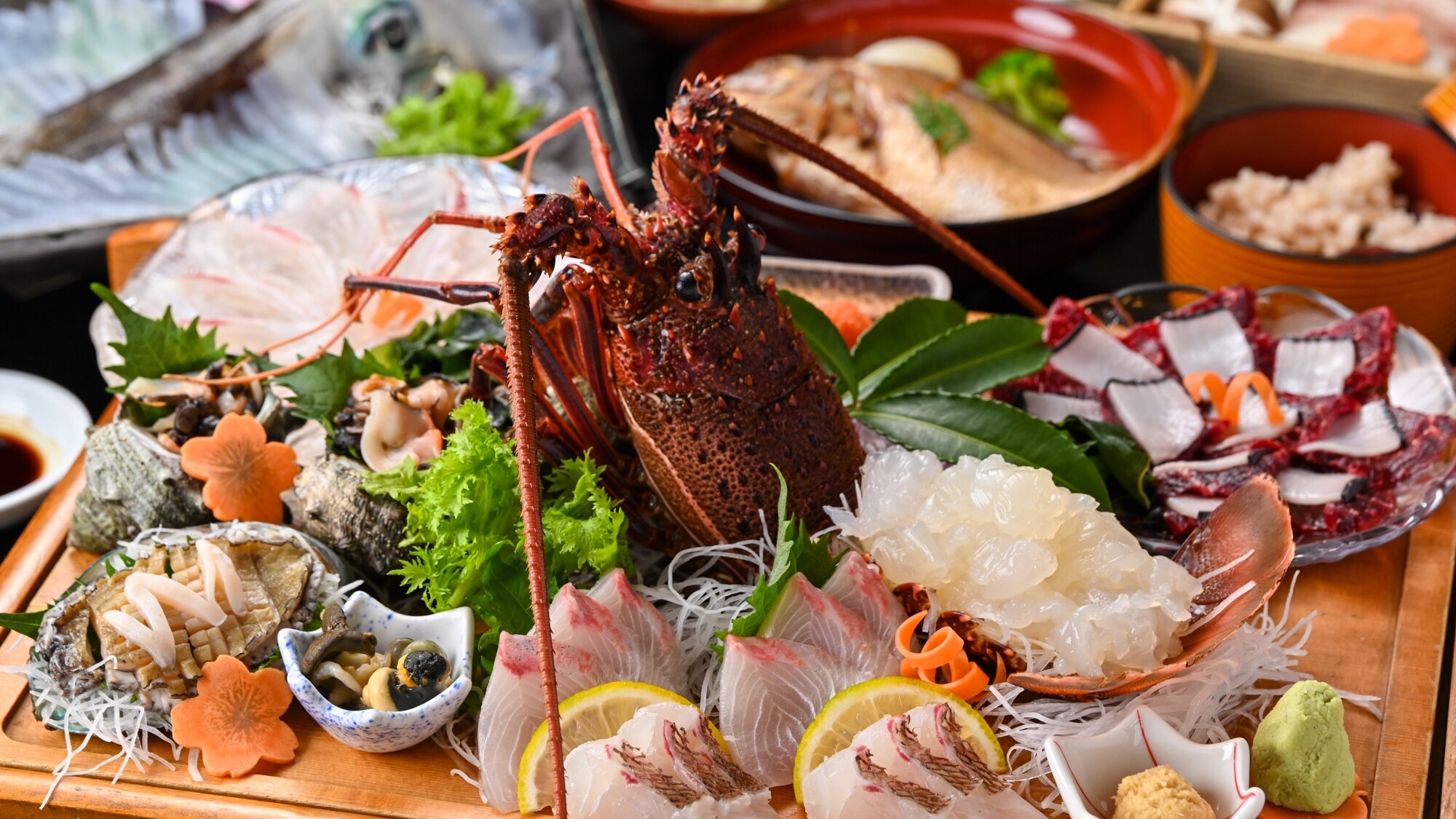 A wide variety of seafood, including sashimi of wild fish from Yobuko, spiny lobster, squid, etc., is presented on a chopping board.
