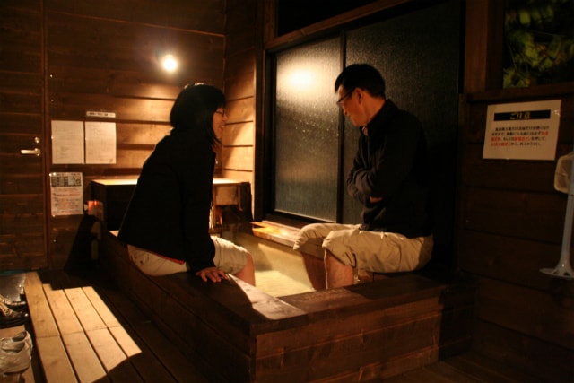 A couple spends precious time chatting while enjoying a foot bath in a condominium with an open-air bath.