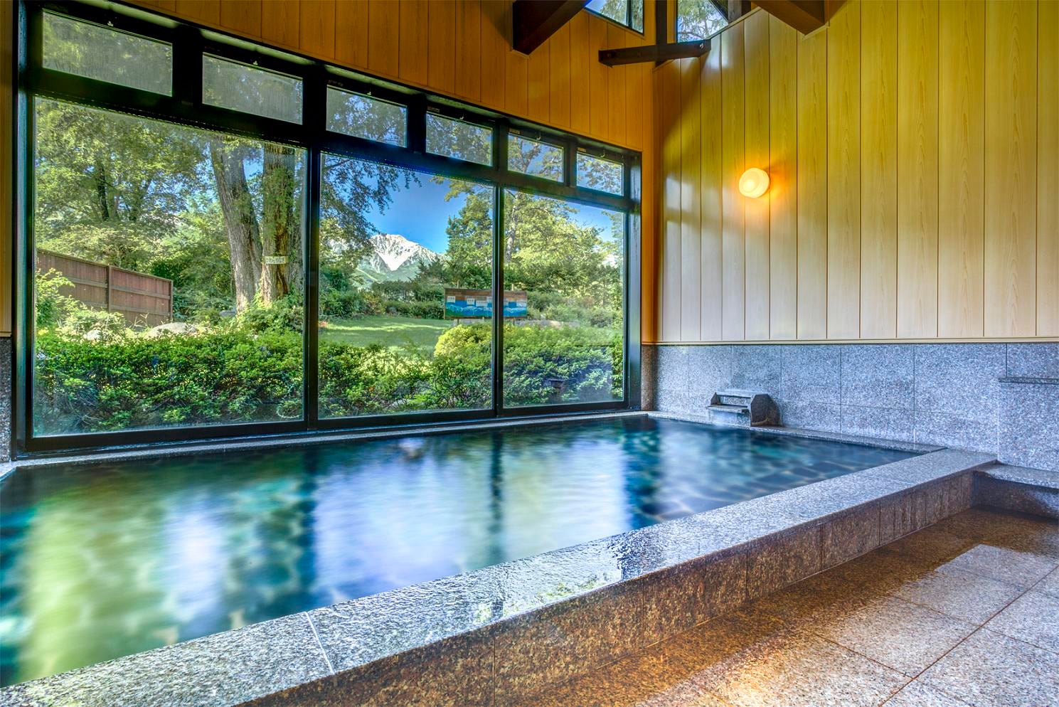 Một bồn tắm lớn được bao quanh bởi cây xanh