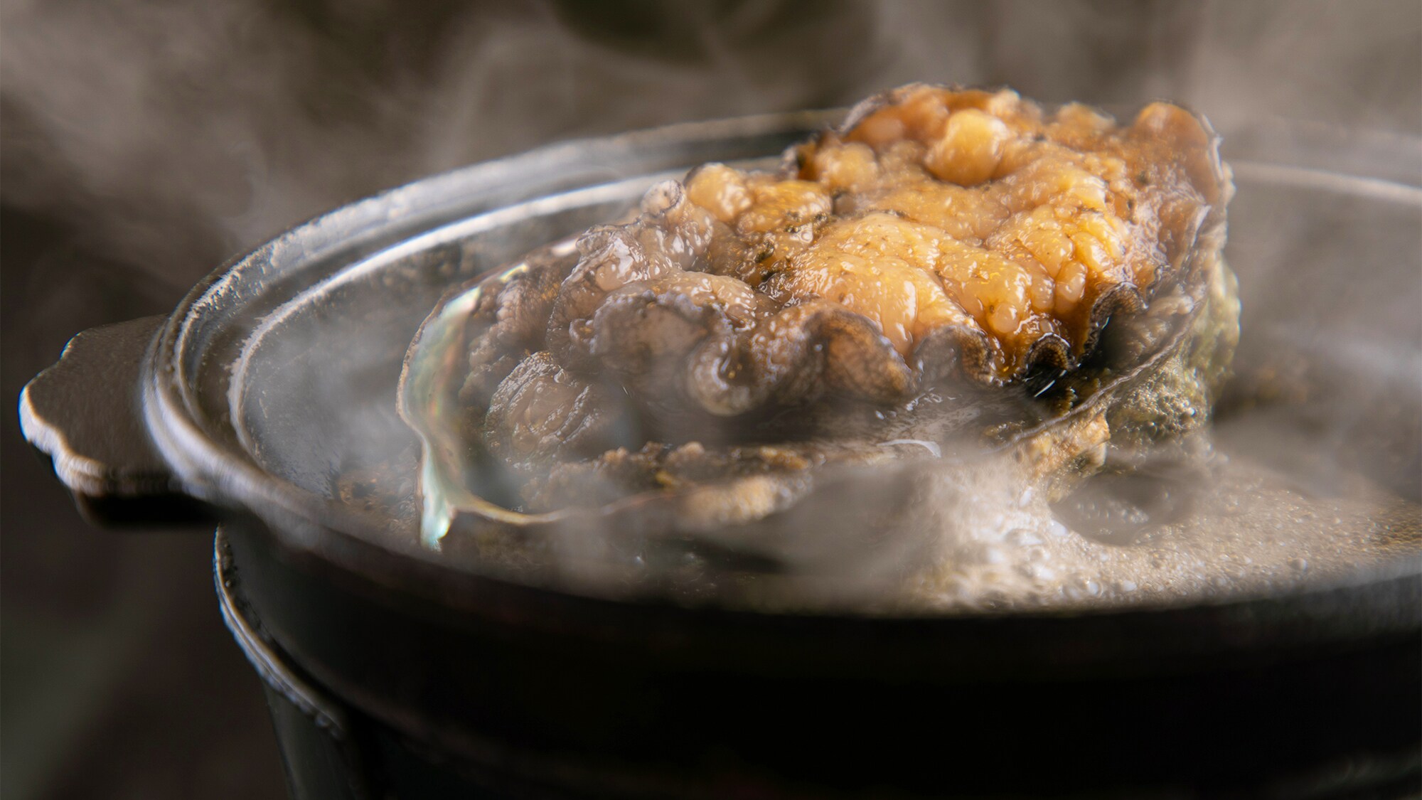 [Live abalone grilled on a ceramic plate]
