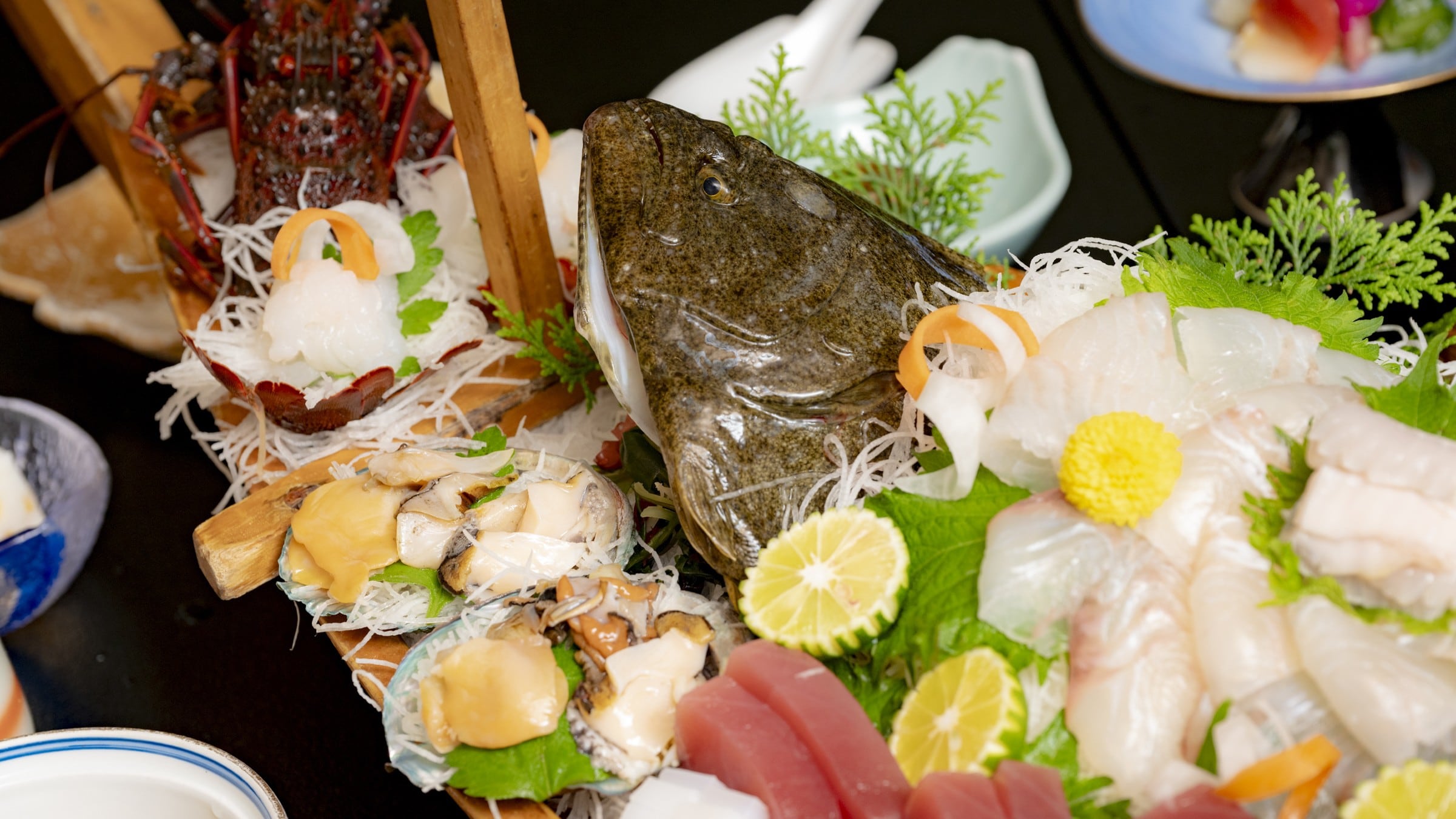 寶船料理範例“盛有龍蝦、鮑魚、比目魚整條刺身等的豪華船形拼盤”
