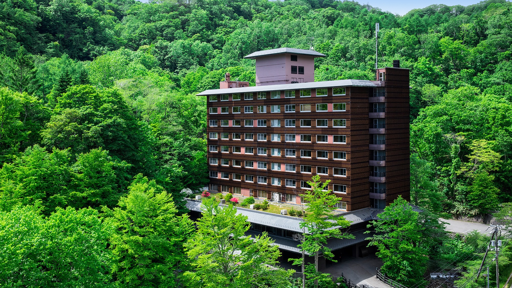 [Ngoại thất] "Bourou NOGUCHI Noboribetsu" tọa lạc tại Noboribetsu Onsen, được bao quanh bởi màu xanh tươi mát của mùa hè