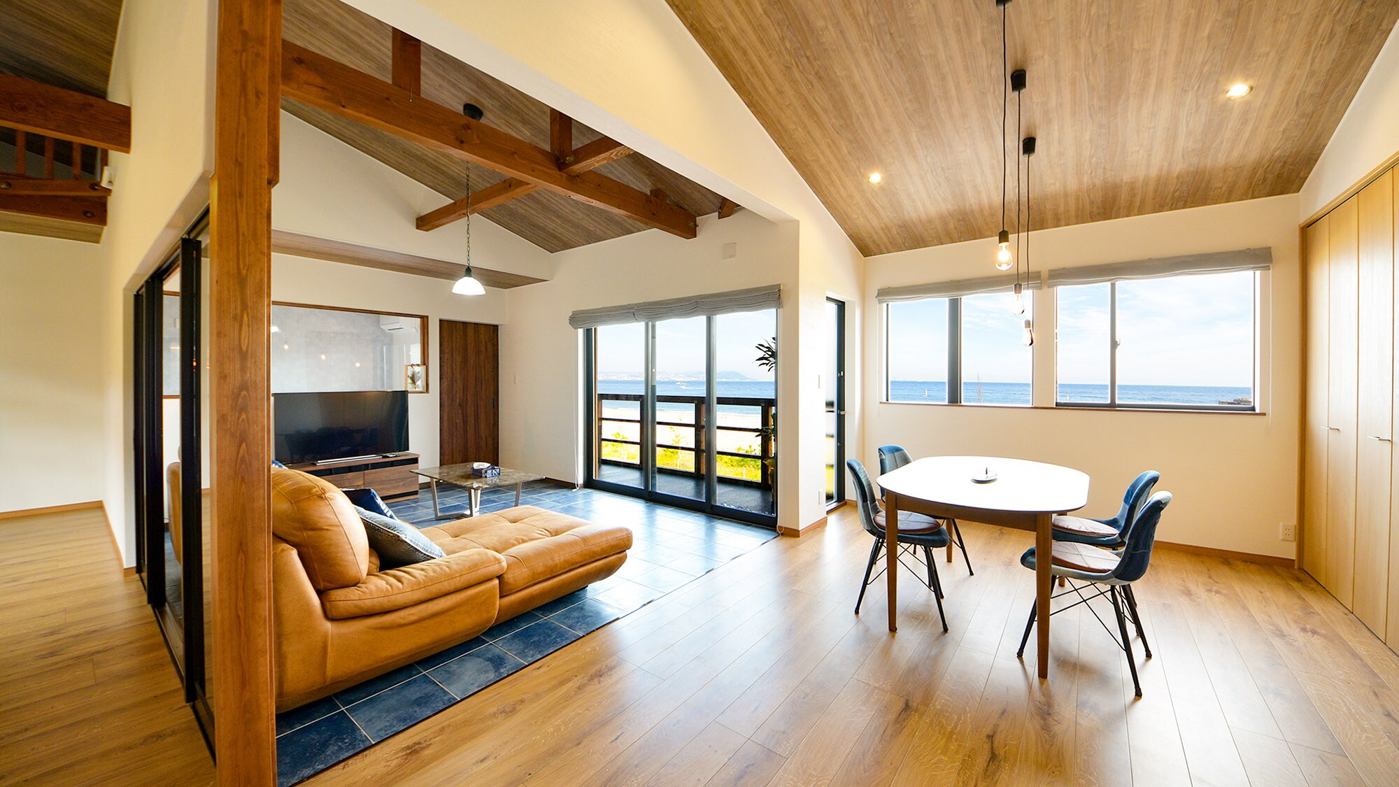 A living/dining room with bright sunlight pouring in through the large windows