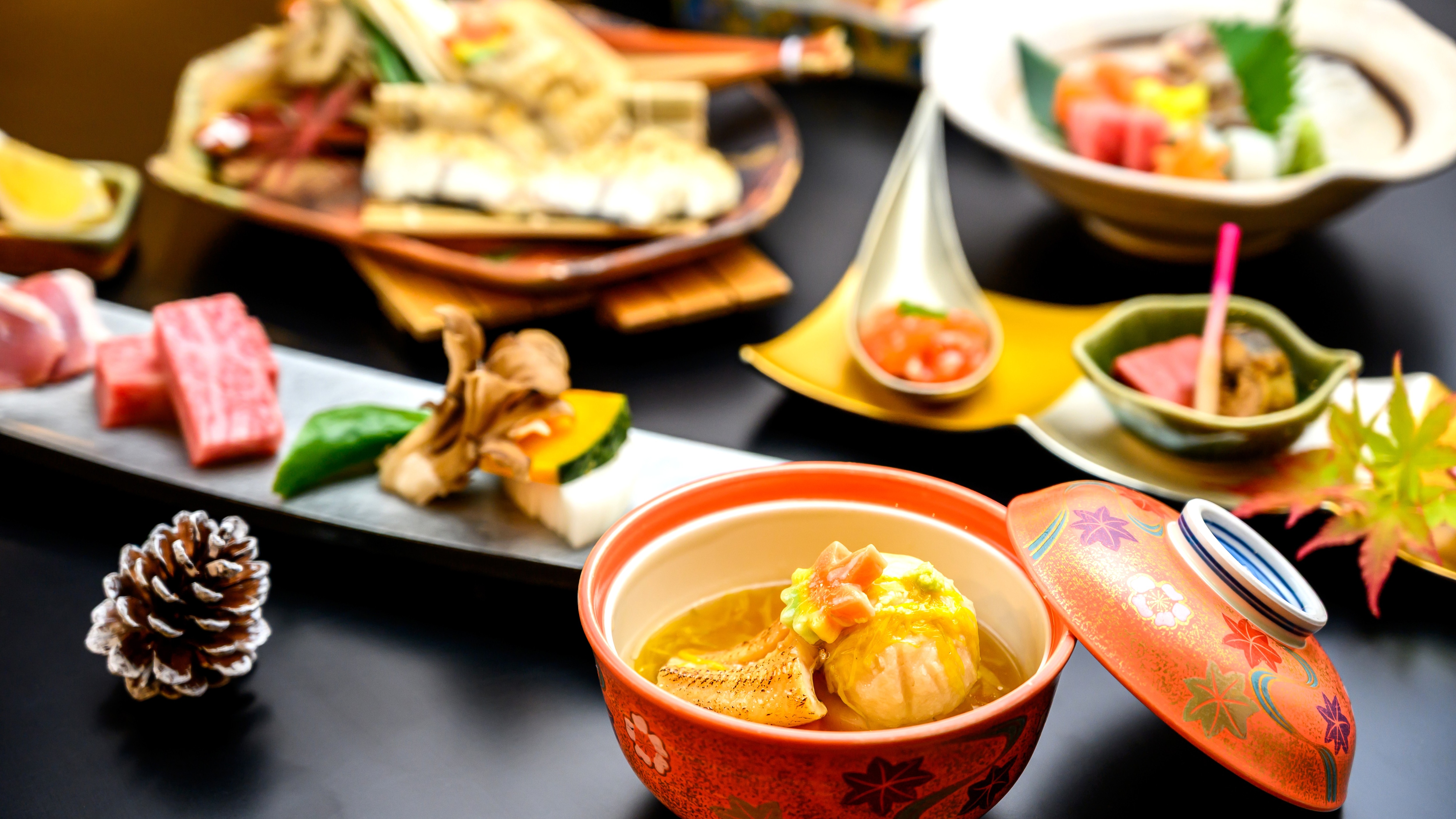 Hidangan kaiseki musiman yang menampilkan belut yang direbus dalam saus gurih dan daging sapi Omi yang dipanggang di atas piring keramik (dengan tema musim gugur).
