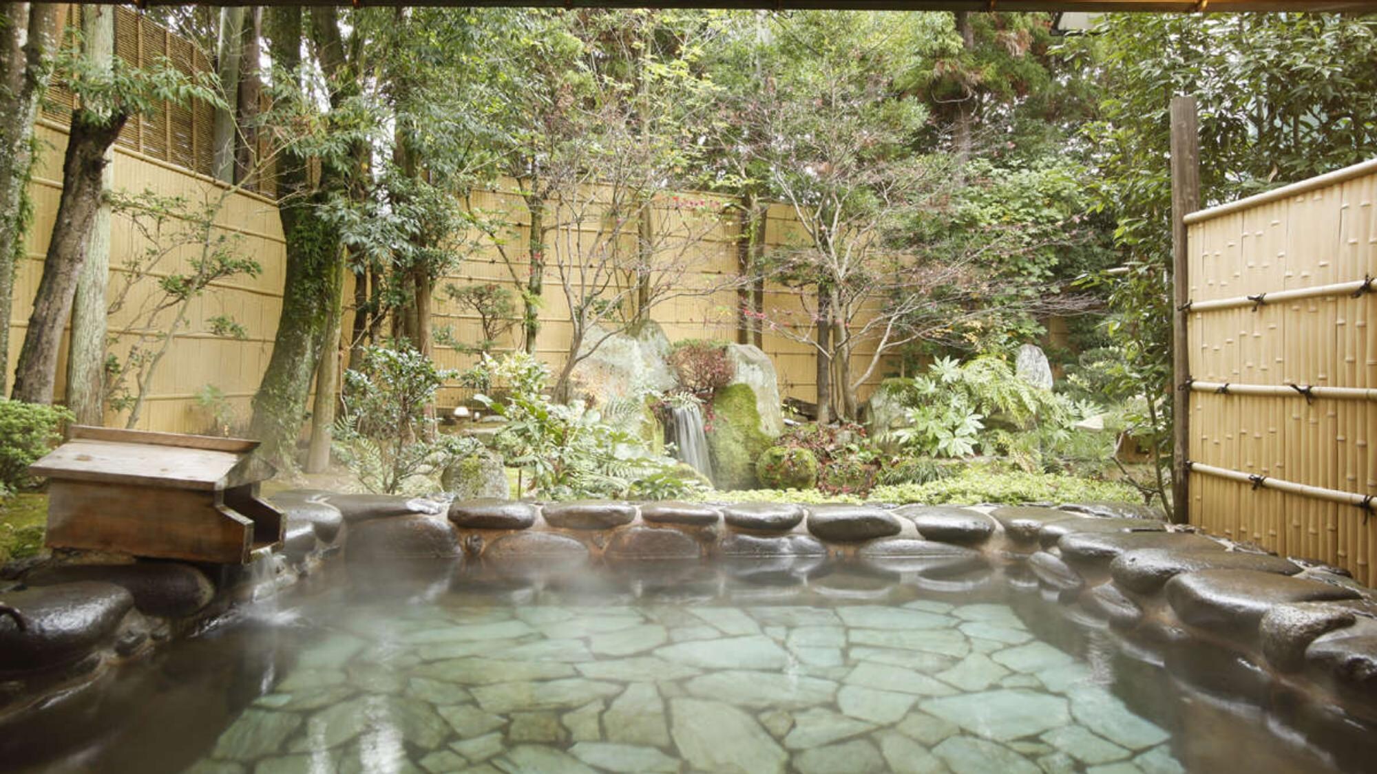 An open-air rock bath surrounded by seasonal flowers. [Open-air bath]