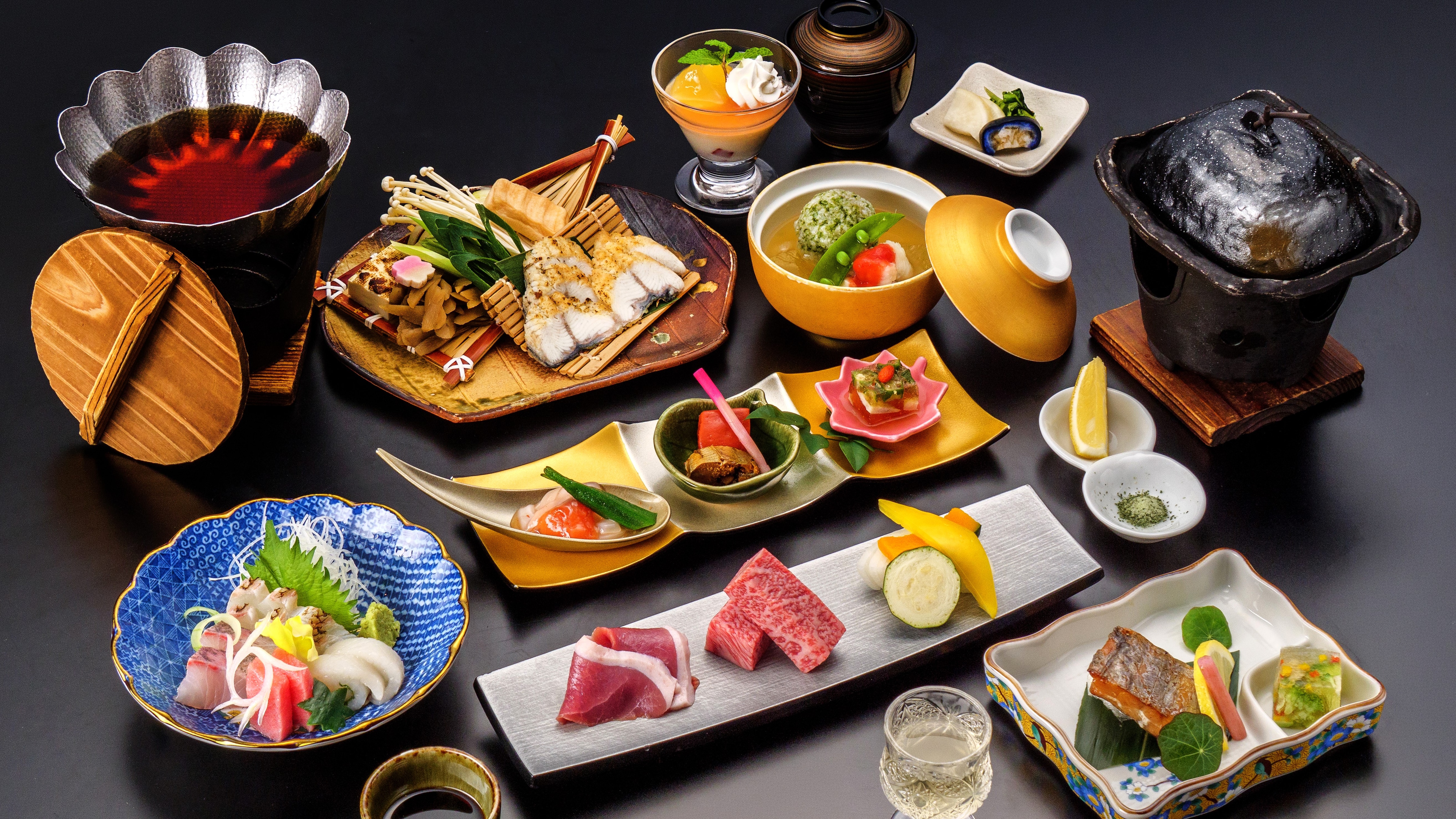 A seasonal kaiseki meal featuring eel simmered in a savory sauce and Omi beef grilled on a ceramic plate (with a summer theme).