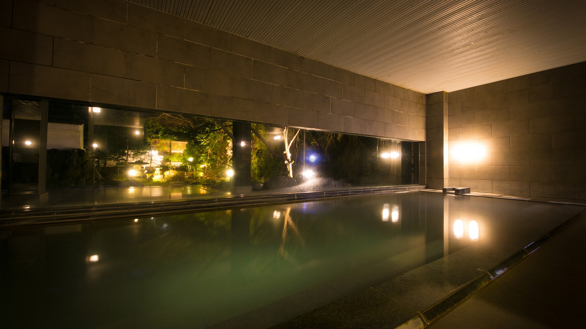 [Large public bath] At night, the illuminated Japanese garden and the milky white water resonate together, creating a fantastical world.