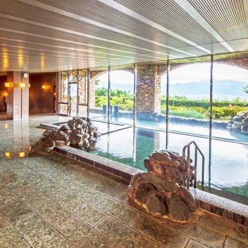 An indoor bath where bright sunlight shines through the large windows