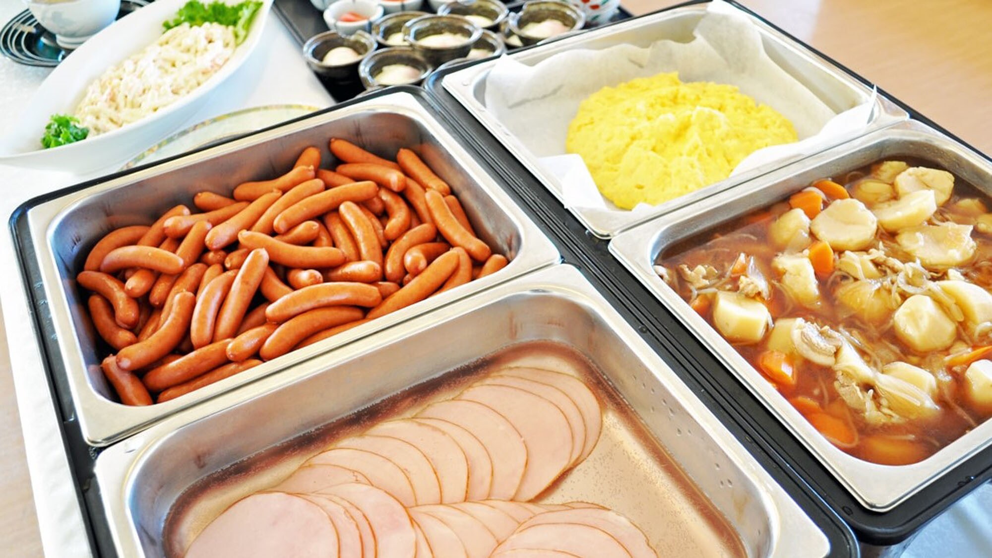 【自助早餐例】 火腿、香腸、肉和馬鈴薯燉菜、雞蛋料理等。