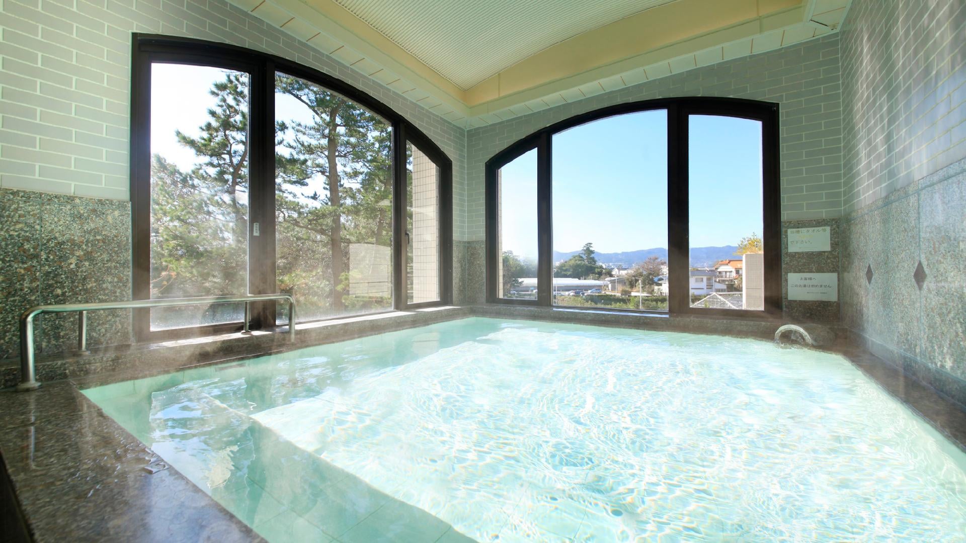 A large public bath overlooking Kamogawa city and the sea in the distance.