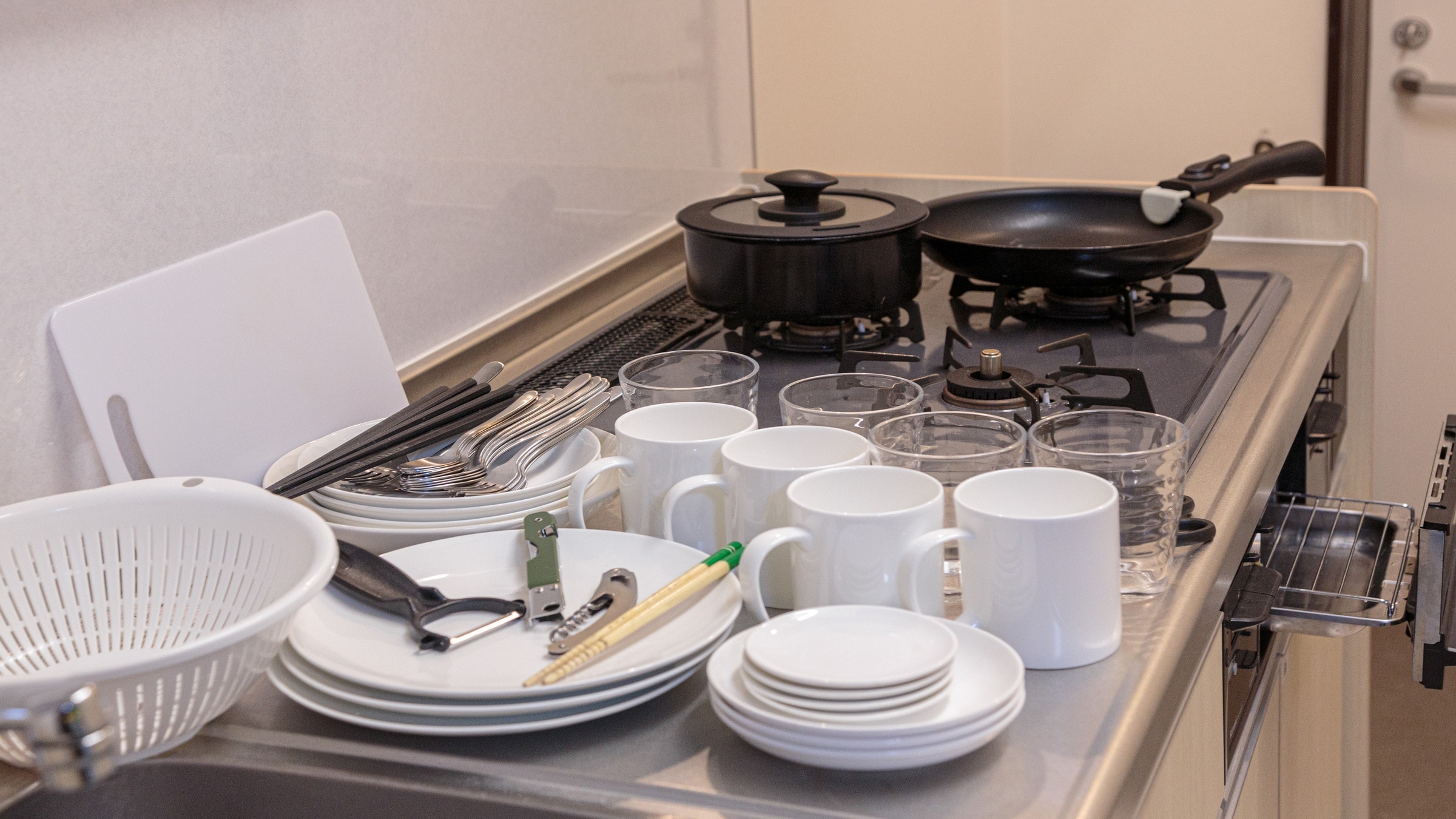 The kitchen is equipped with frying pans, cooking utensils and tableware.