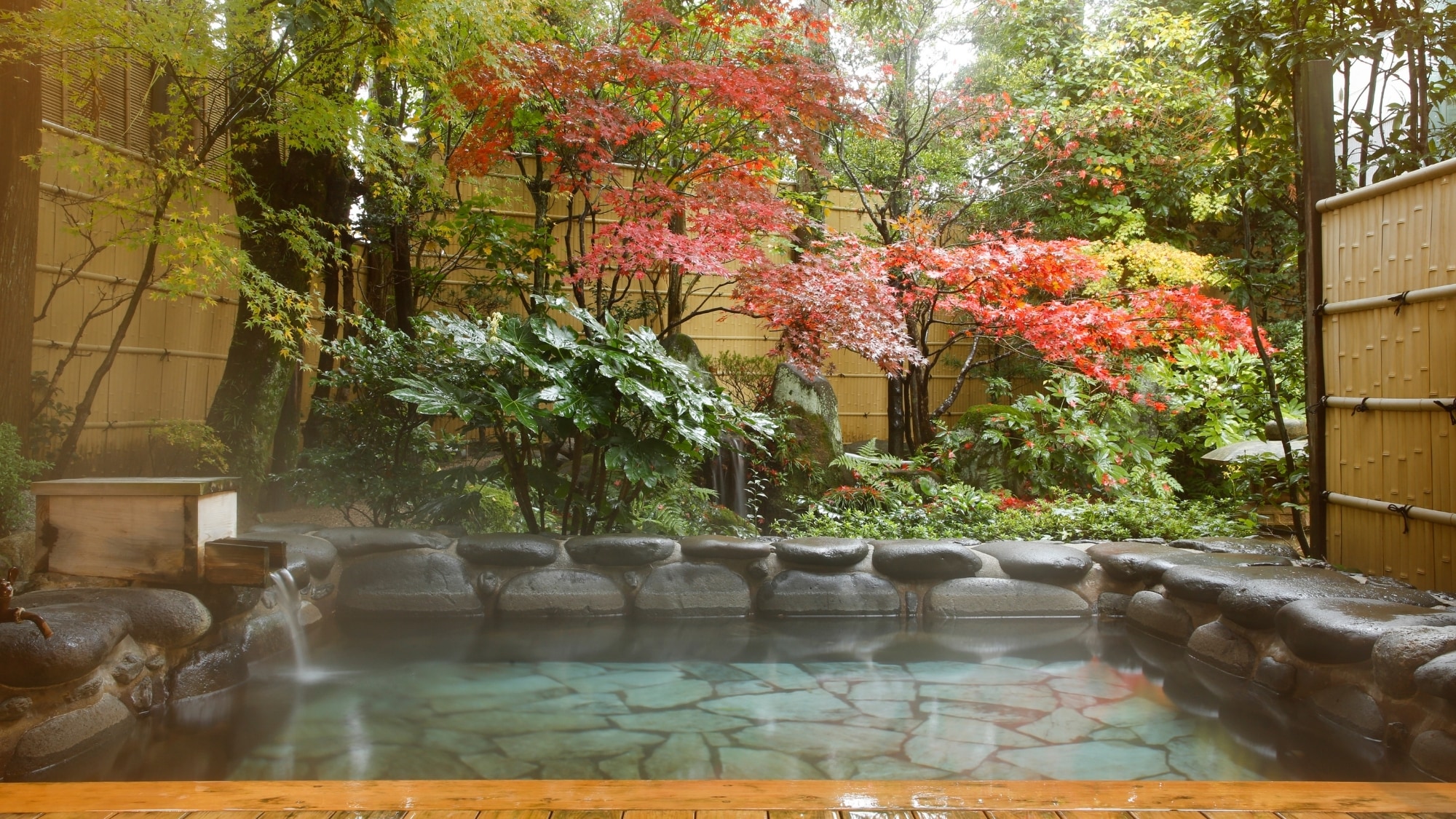 An open rock bath surrounded by flowers of the four seasons