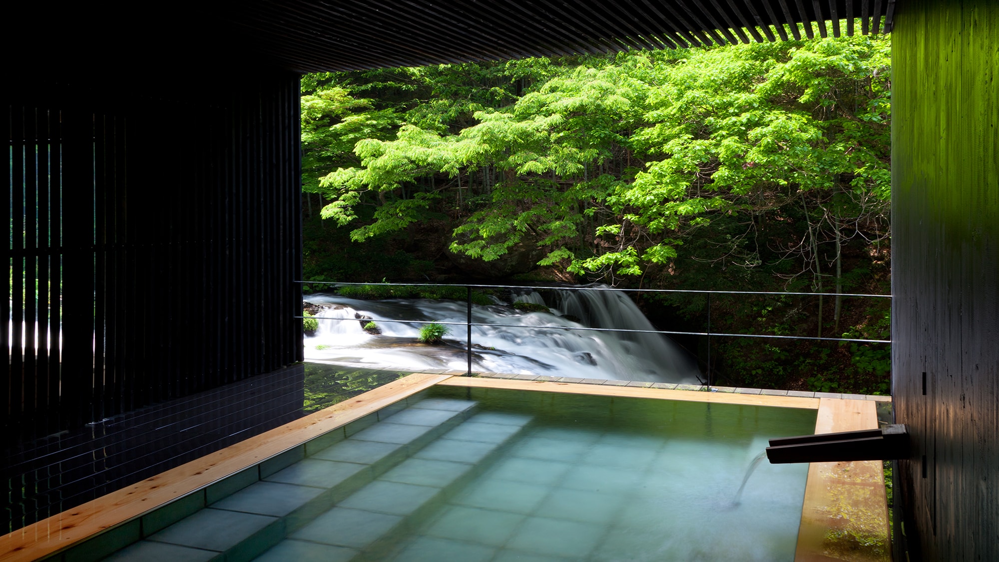 An image of "Takimi no Yu", an open-air bath with a spectacular view of Aizu's famous waterfall "Fushimigataki" ♪