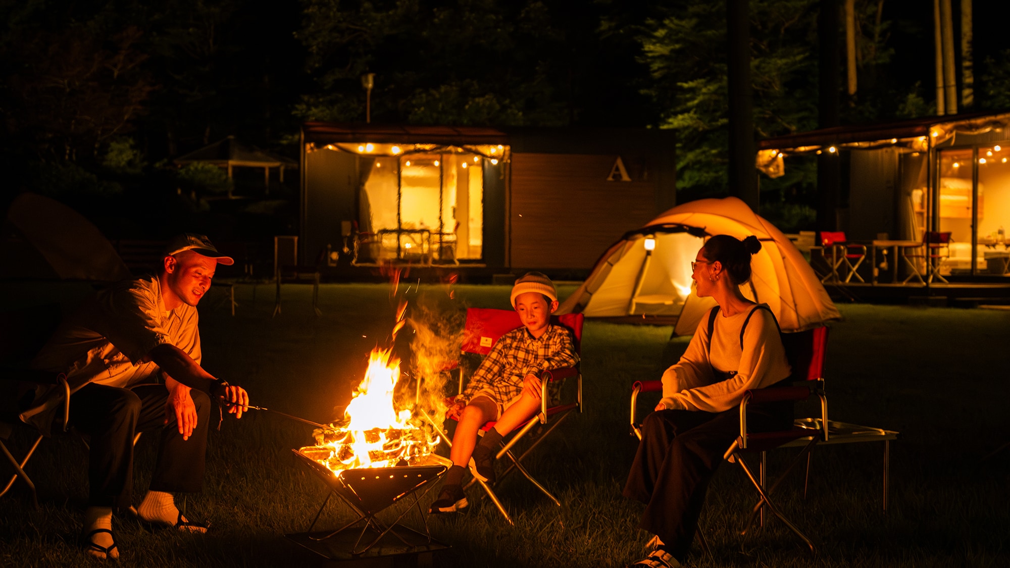 Under the quiet, starry night sky, the flickering light of the bonfire creates a relaxing moment.